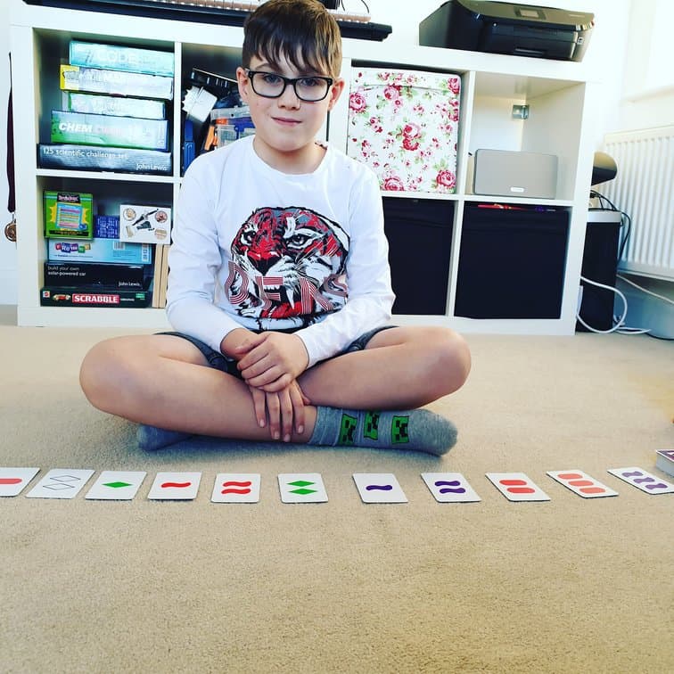 Boy sitting in front of SET the family game of visual perception 