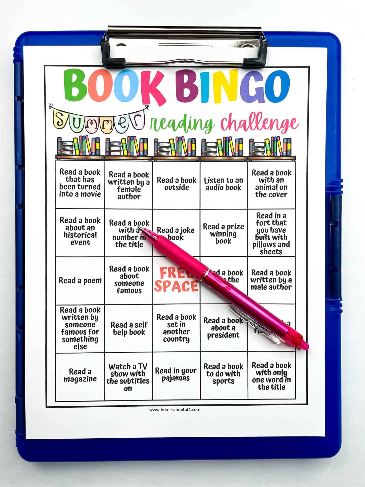 A colorful “Book Bingo” summer reading challenge sheet is clipped to a blue clipboard with a pink pen resting diagonally across it. The bingo grid includes creative reading prompts like “Read a joke book,” “Read a book written by someone famous for something else,” and “Read in your pajamas,” encouraging kids to explore different types of reading.