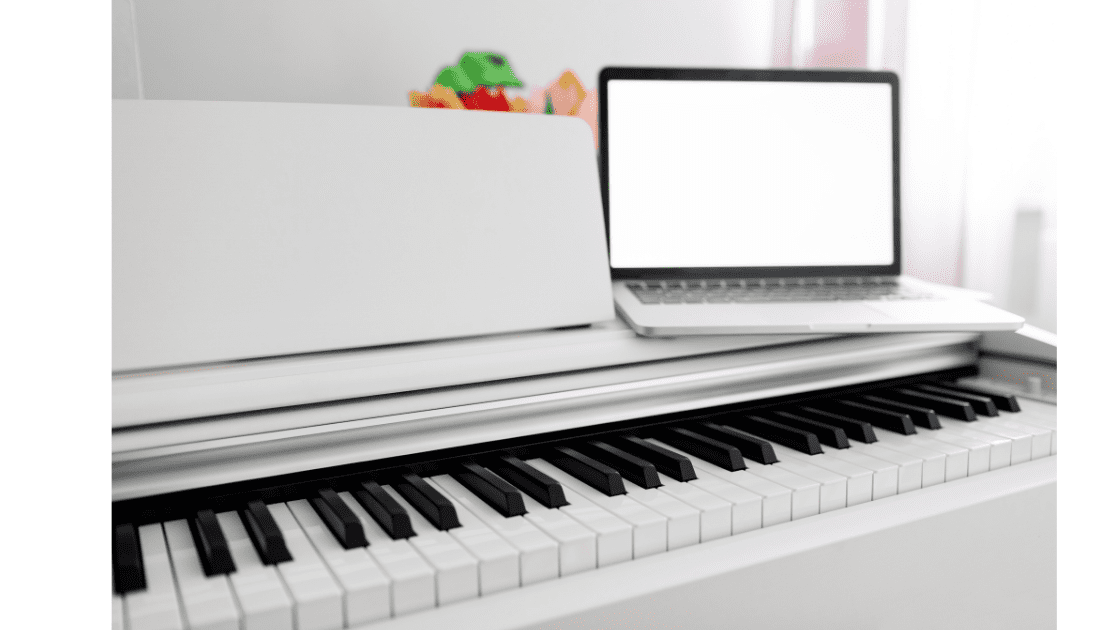White piano with white laptop on top.