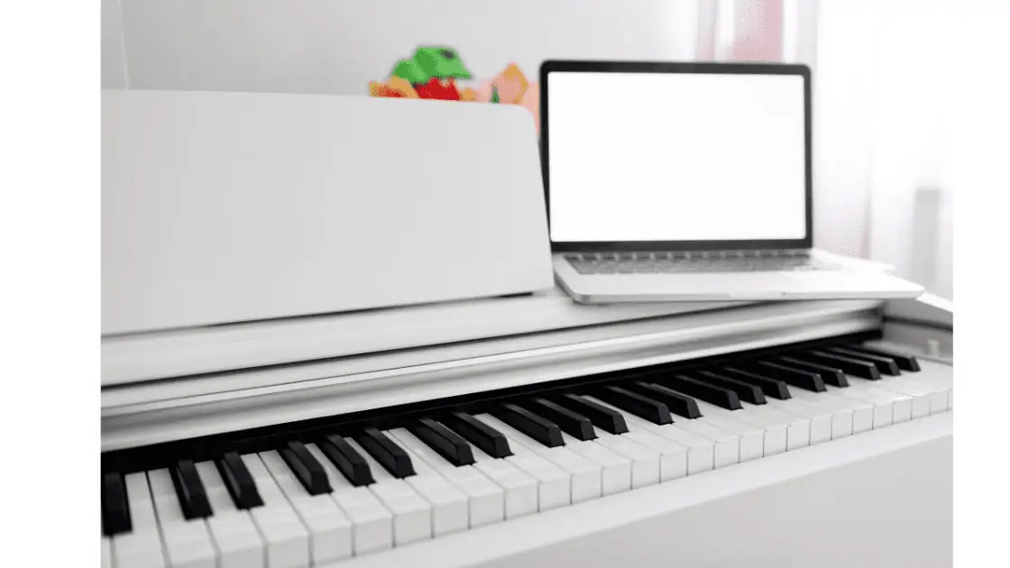 White piano with white laptop on top.
