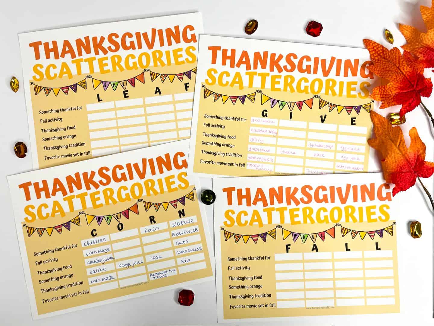 Four printable Thanksgiving Scattergories game cards featuring festive fall designs with the words LEAF, GIVE, CORN, and FALL at the top of each sheet. Each card has prompts like “something thankful for” and “Thanksgiving food,” surrounded by autumn leaves and colorful gems for a fun, seasonal word game.