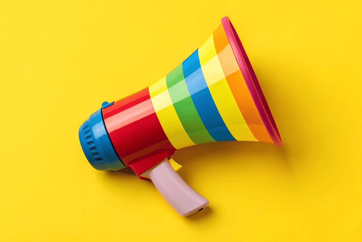 Colorful rainbow-striped toy megaphone on a bright yellow background, symbolizing kids gaining confidence through online public speaking classes.