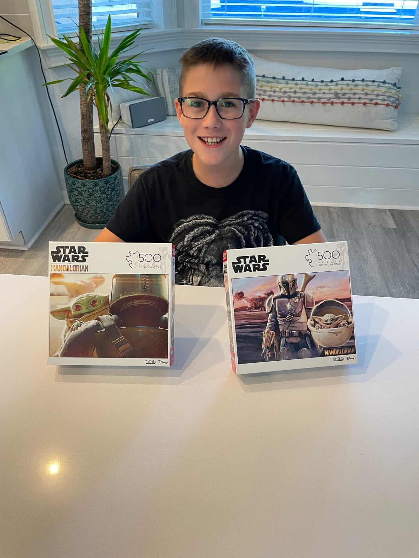 Boy holding 2 Star Wars puzzles.