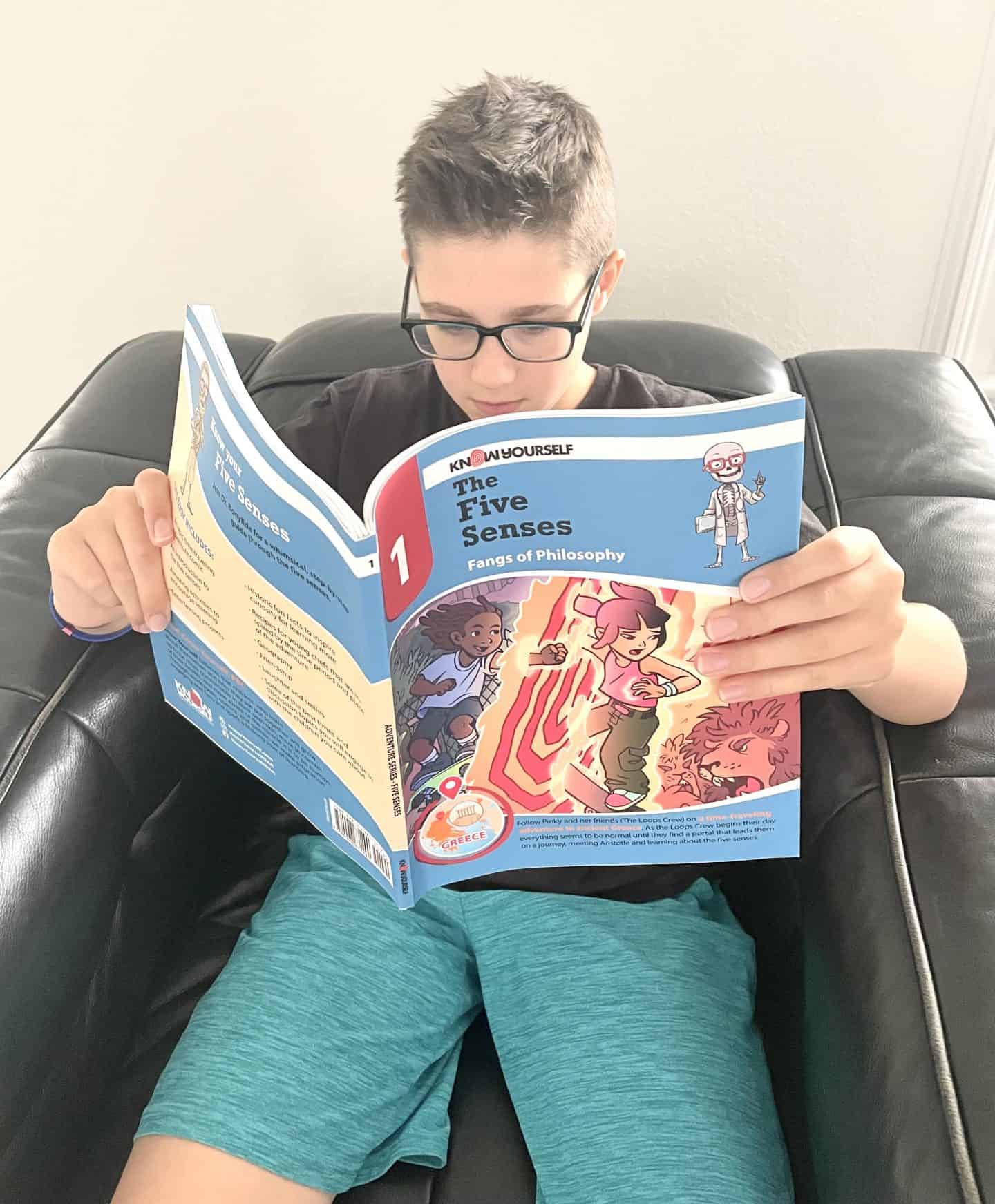 Young boy sitting on a chiary reading Know Yourself Book The Five Senses Fangs of Philosophy