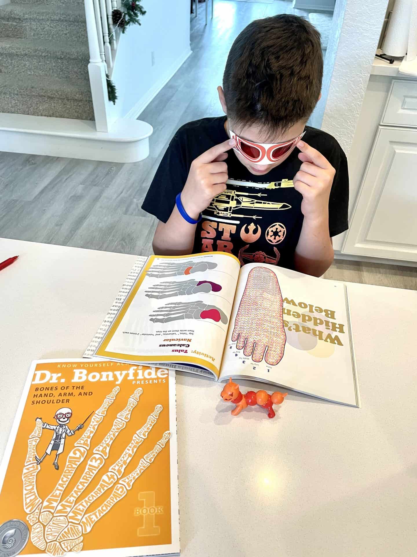 Young boy wearing 3d glasses looking though a Dr Bonyfide Book for Kids