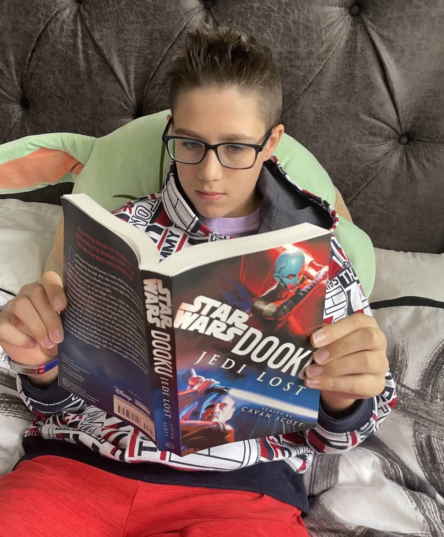 13 year old reading star wars Dooku Jedi Lost book on his bed. 