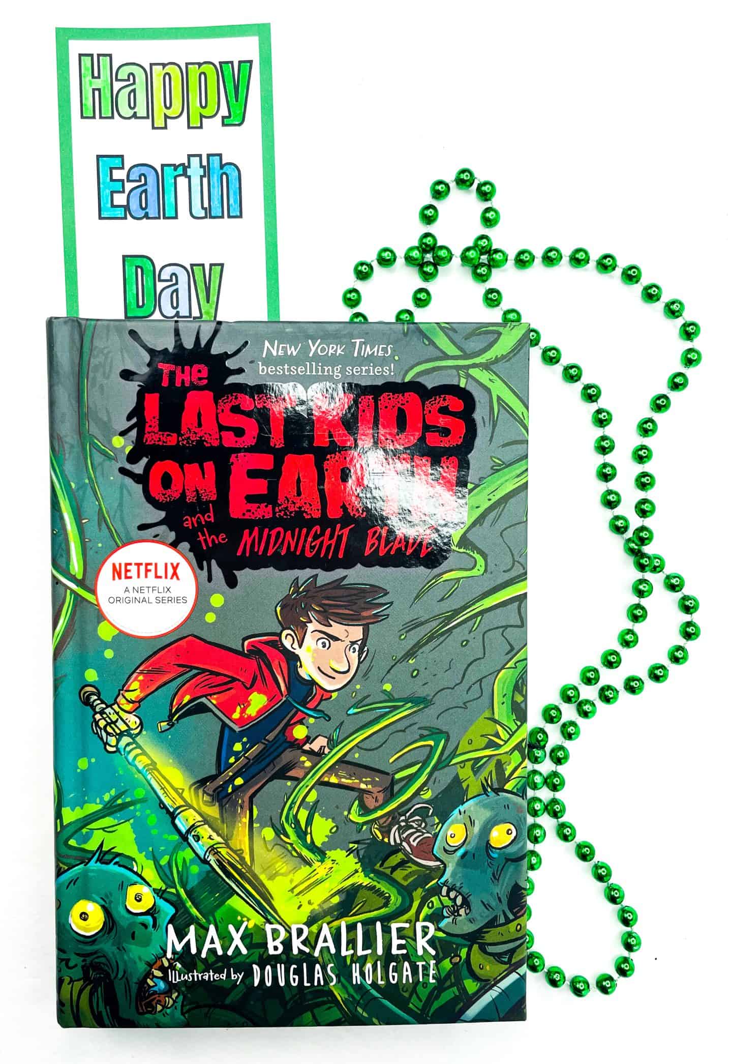 A set of Earth Day bookmarks placed beside the book The Last Kids on Earth, featuring colorful hand-colored illustrations like a globe, flowers, and the words “Love the Earth.” One bookmark is tucked into the book like a real reader would.

