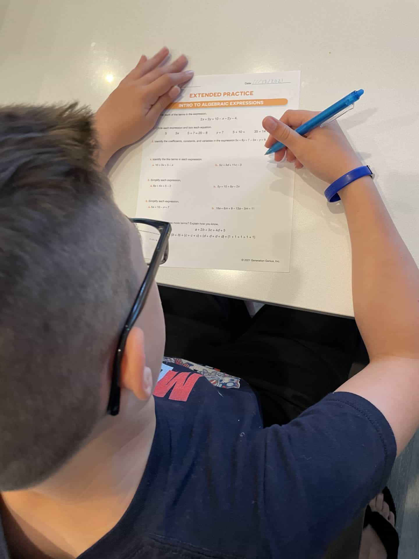 boy completing generation genius math extended practice on paper