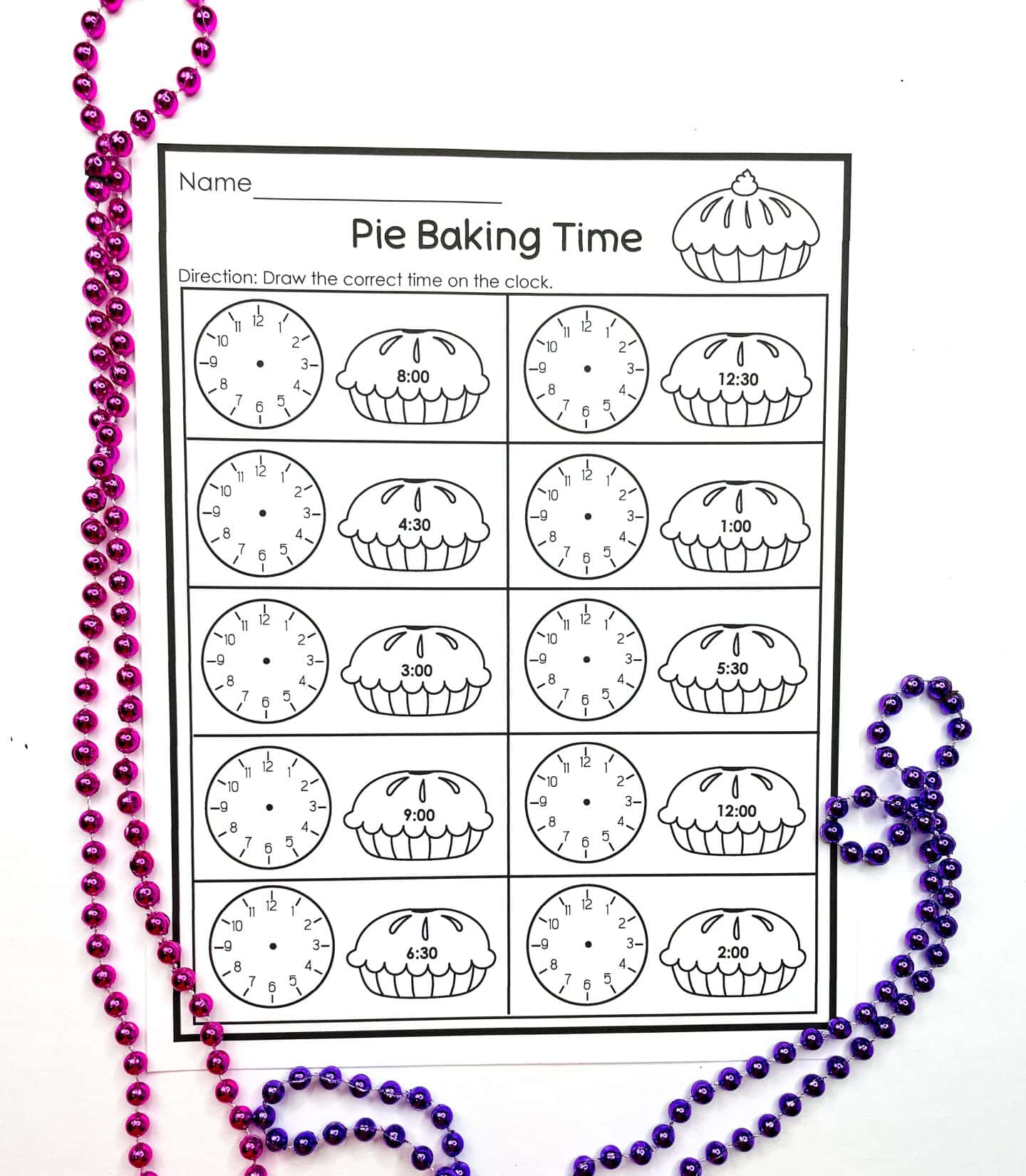 A pie baking time worksheet featuring twelve blank analog clocks paired with labeled pie illustrations showing different times such as 8:00, 4:30, and 12:30. Students are instructed to draw the correct time on each clock. The page is surrounded by festive pink and purple beaded necklaces.