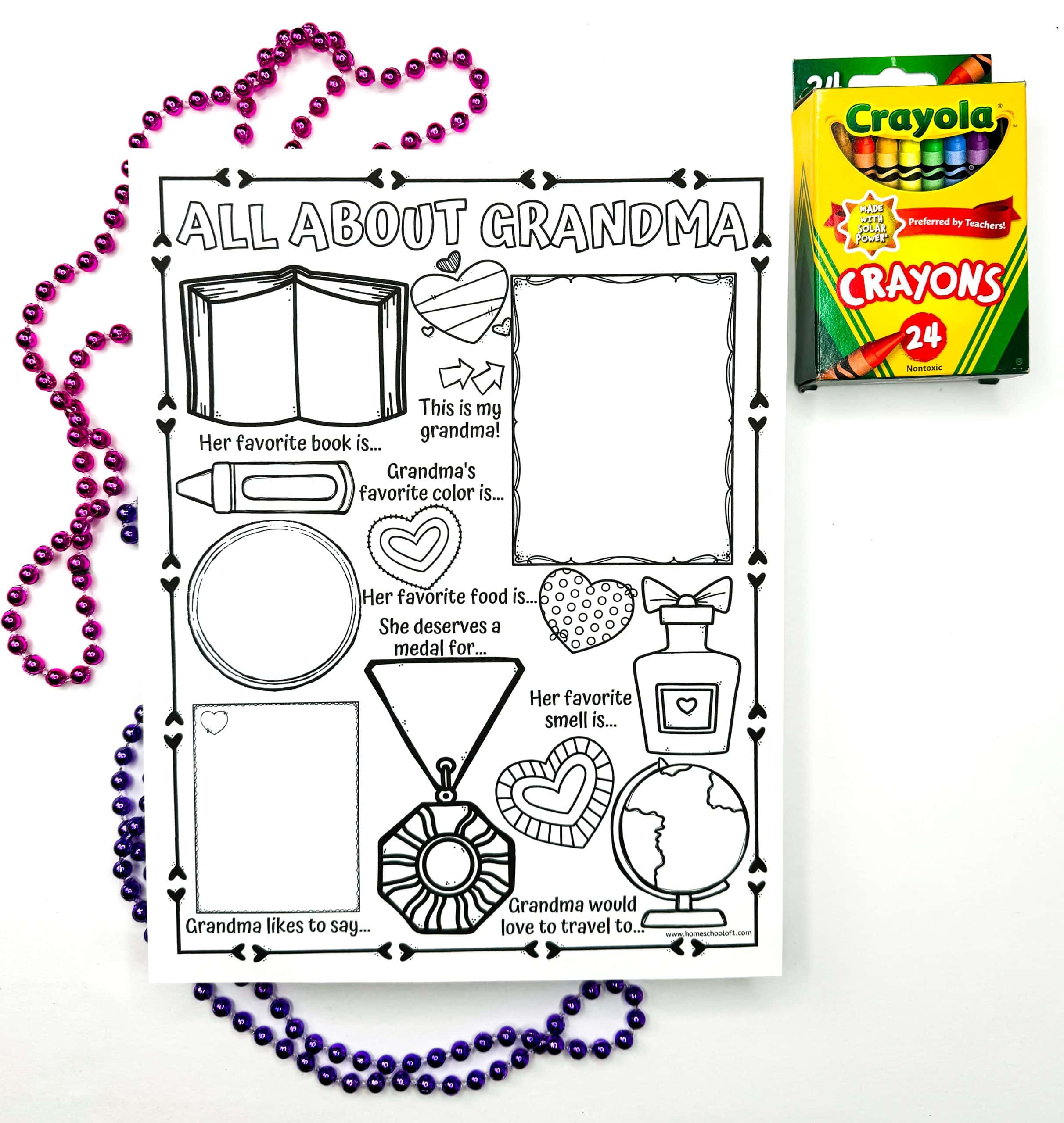A black-and-white printable worksheet titled “All About Grandma,” surrounded by pink and purple beaded necklaces, with a box of 24 Crayola crayons nearby. The worksheet features blank sections for kids to fill in details like Grandma’s favorite book, color, food, smell, a drawing or photo, and what she deserves a medal for, along with decorative icons like a heart, globe, and medal.