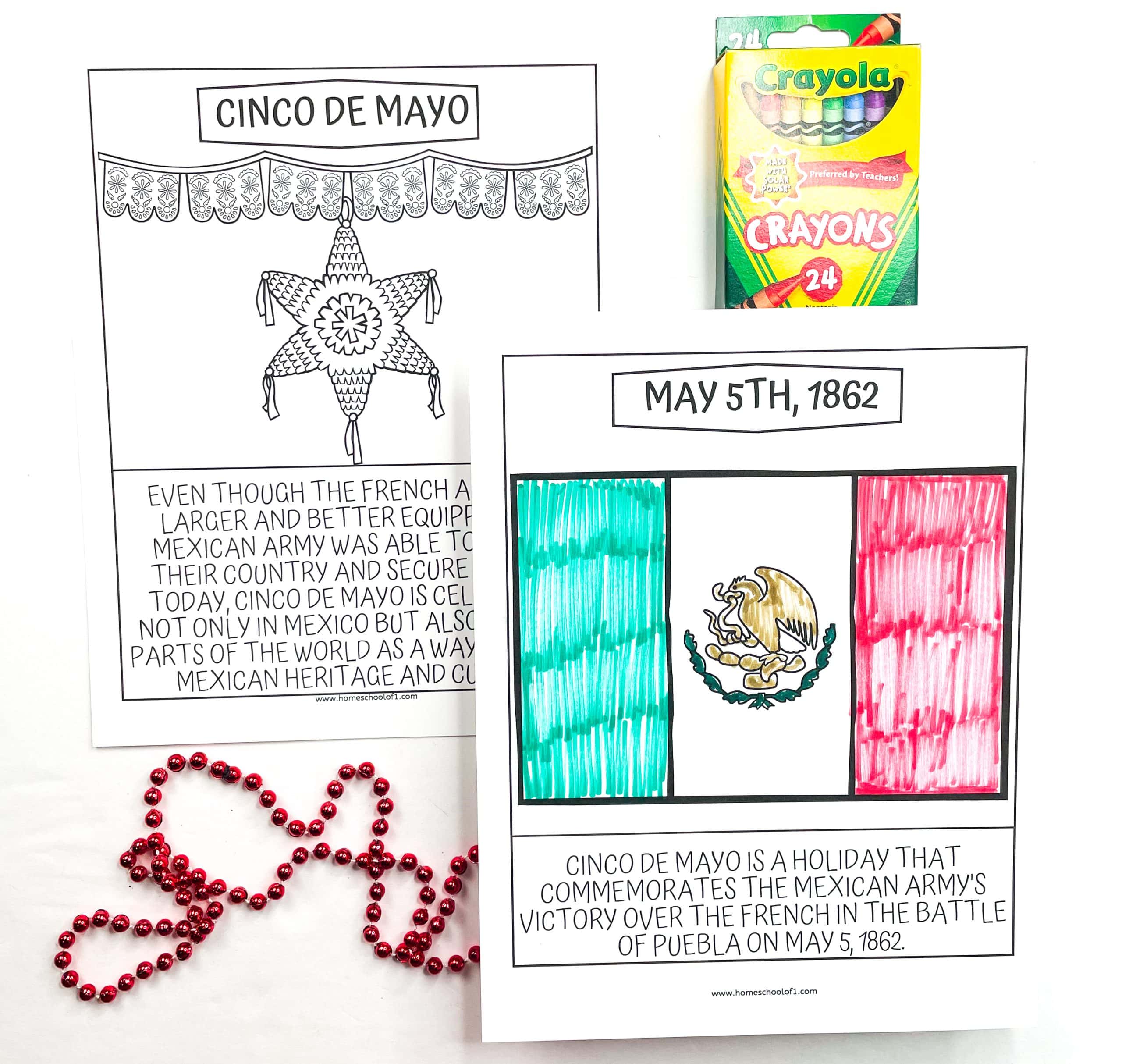 Two educational Cinco de Mayo coloring pages for kids. One page features a piñata with papel picado decorations and a paragraph explaining the historical significance of Cinco de Mayo. The second page shows a hand-colored Mexican flag labeled “May 5th, 1862” and describes the Mexican army’s victory over the French at the Battle of Puebla. A pack of Crayola crayons and red bead garland are also included in the scene.

