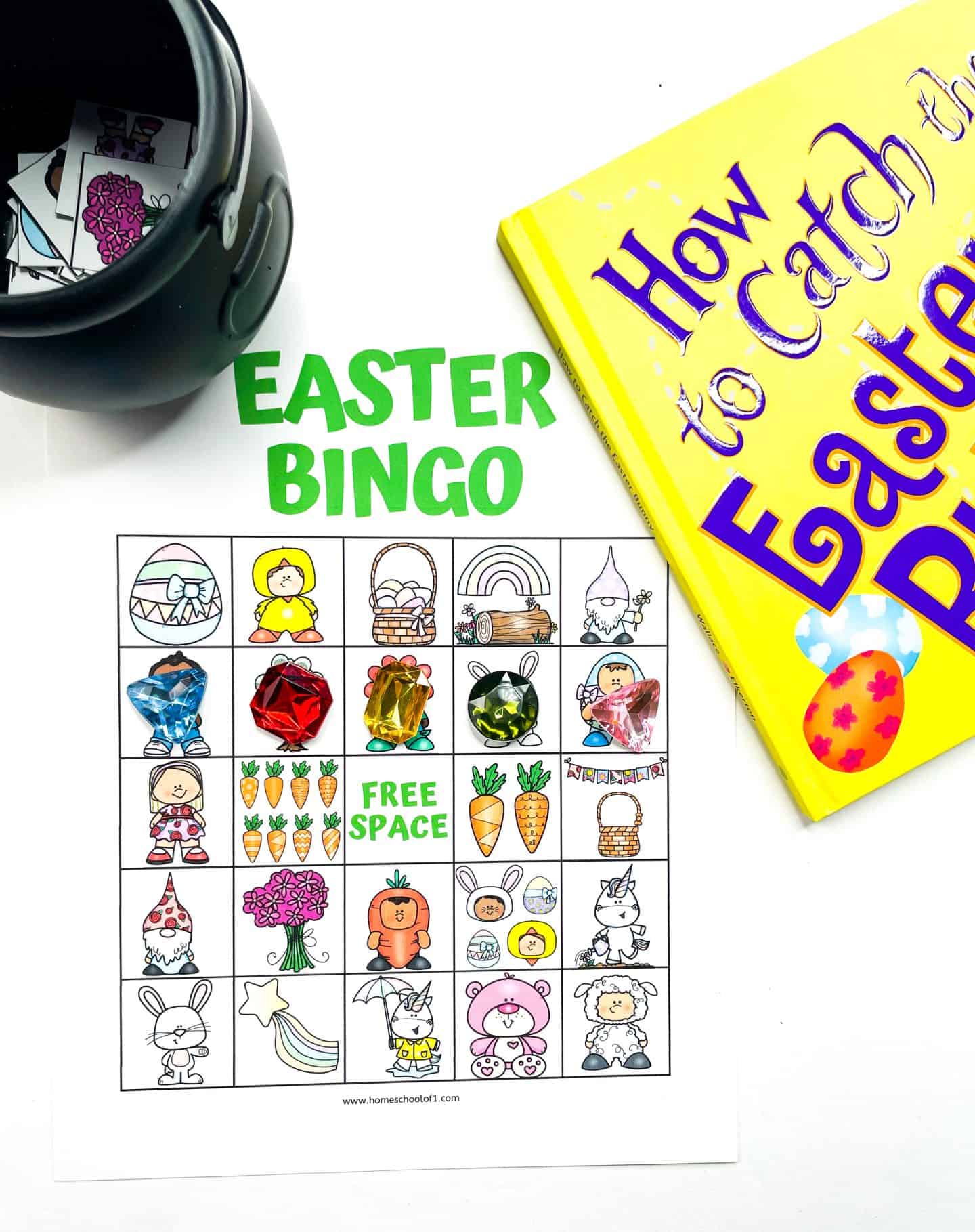 Colorful Easter bingo board filled with festive cartoon images such as bunnies, chicks, rainbows, Easter eggs, baskets, carrots, and more. Some squares are marked with large gem-style game markers. A black pot filled with calling cards and a yellow children’s book titled How to Catch the Easter Bunny sit nearby, creating a playful and engaging Easter activity setup