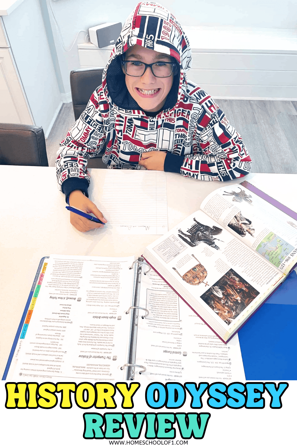 Middle school student sitting at a table working on a History Odyssey lesson, with the curriculum binder and a history reference book open in front of him.