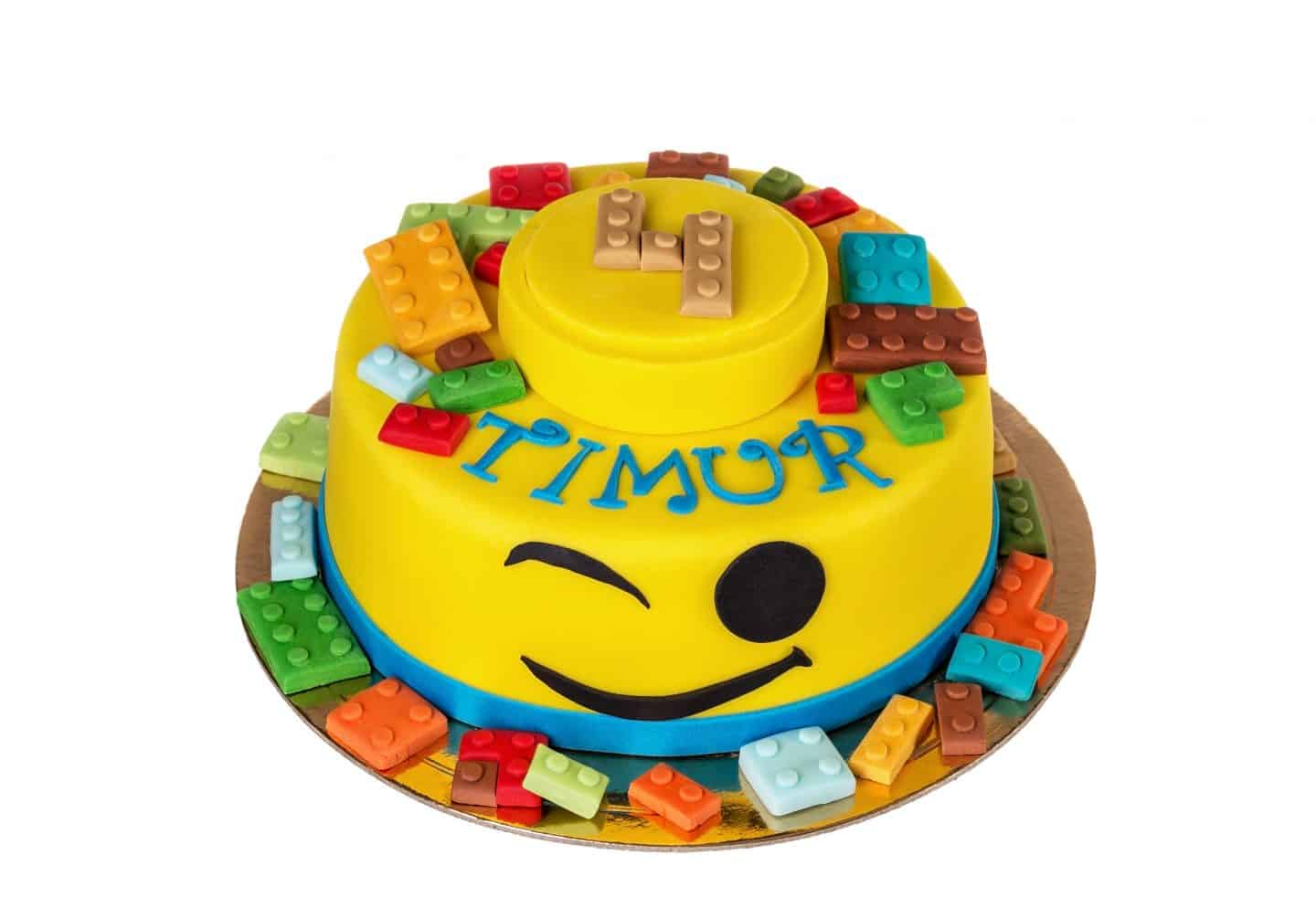 Yellow cake in the shape of lego minifigure head with lego bricks.