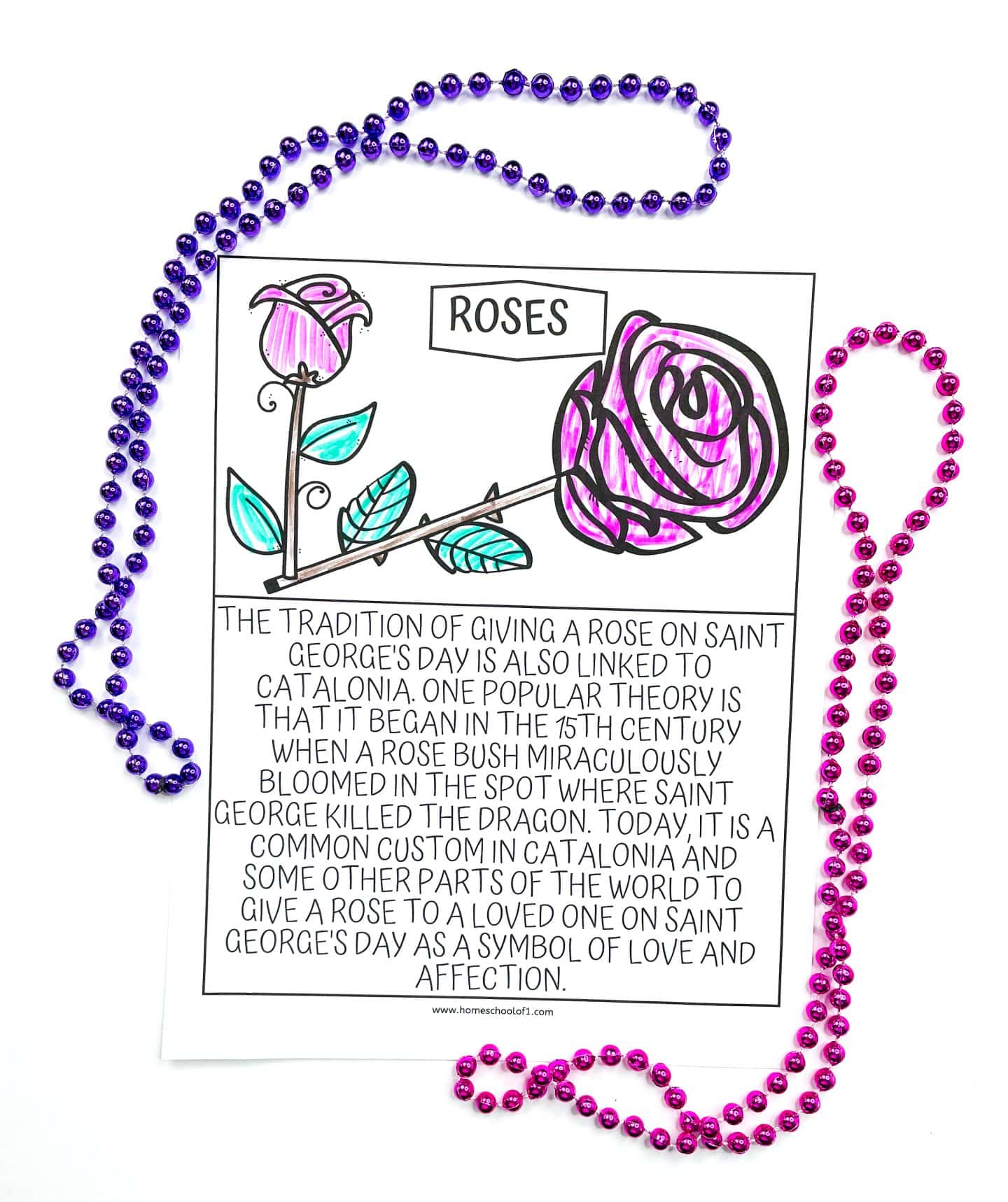 A children's coloring page titled "Roses," featuring two illustrated rose flowers with pink petals and green leaves, partially colored in. The caption below describes the Catalonian tradition of giving a rose on Saint George’s Day, which is believed to have started in the 15th century when a rose bush bloomed where Saint George killed the dragon. The page is surrounded by purple and pink beaded necklaces.

