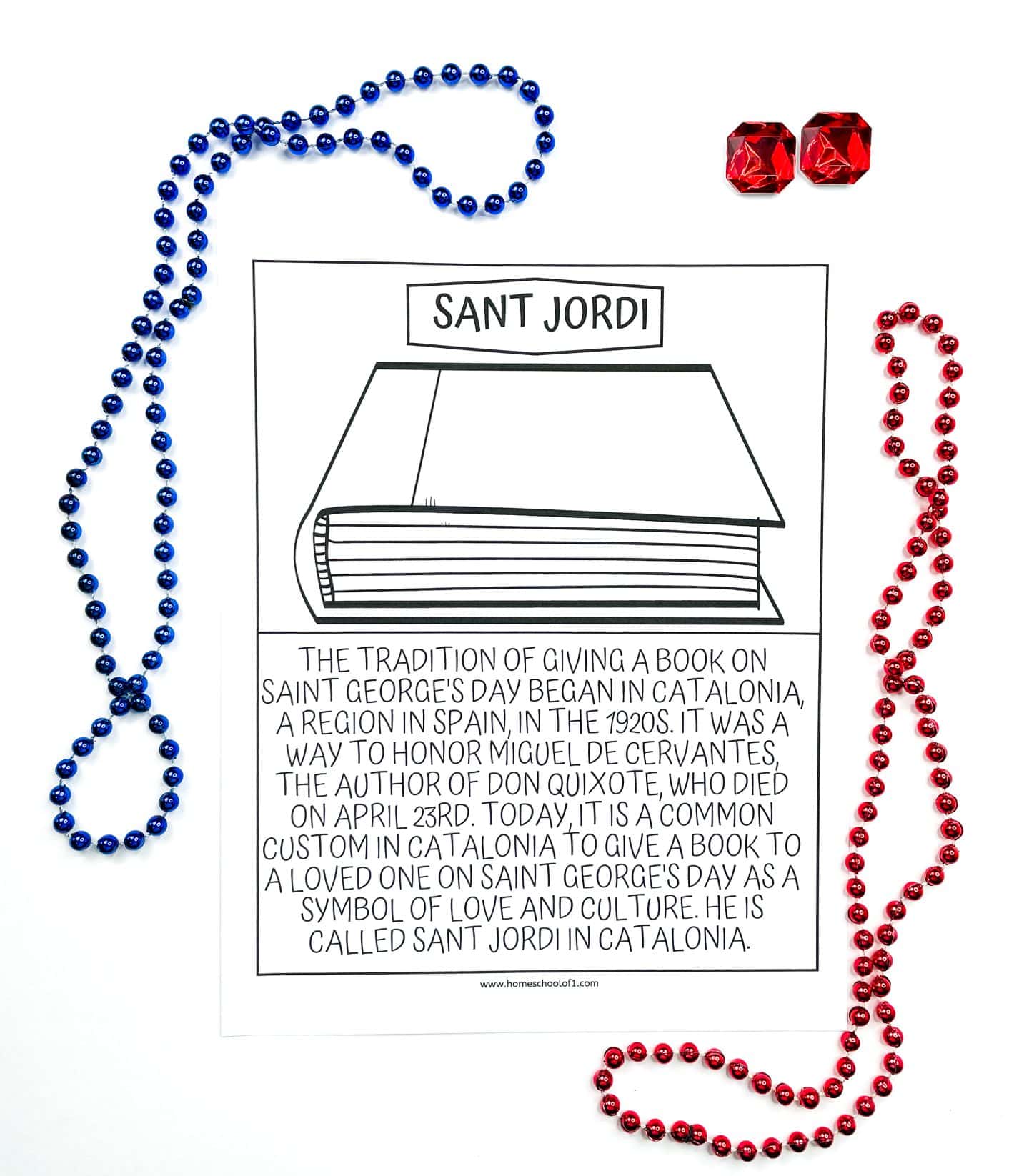 A black-and-white children’s coloring page titled "Sant Jordi," featuring a simple drawing of a closed book. The text below explains the tradition in Catalonia, Spain, of giving a book to a loved one on Saint George’s Day, which began in the 1920s to honor author Miguel de Cervantes. The page is framed by red and blue bead necklaces and two red faux gemstones.

