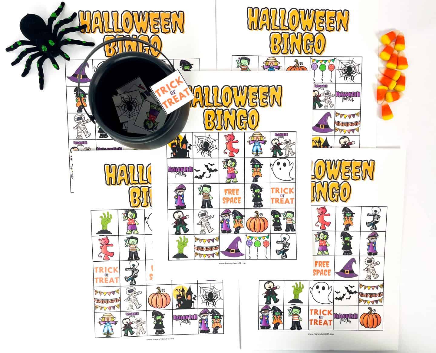 Several Halloween-themed bingo cards are spread out, each decorated with spooky icons like mummies, witches, pumpkins, ghosts, spider webs, and “Trick or Treat” squares. A black cauldron holds matching bingo tiles, with a plush spider and scattered candy corn adding to the festive Halloween vibe. The bold "Halloween Bingo" title is printed on each card.







