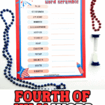 A red, white, and blue Fourth of July word scramble activity page with 15 scrambled patriotic words, placed on a white surface and surrounded by red and blue bead necklaces and a sand timer. The title reads “4th of July word scramble,” and the scramble includes words like “YLJU,” “HOTFUR,” and “EISPTR.” Decorative fireworks and patriotic graphics accent the corners.