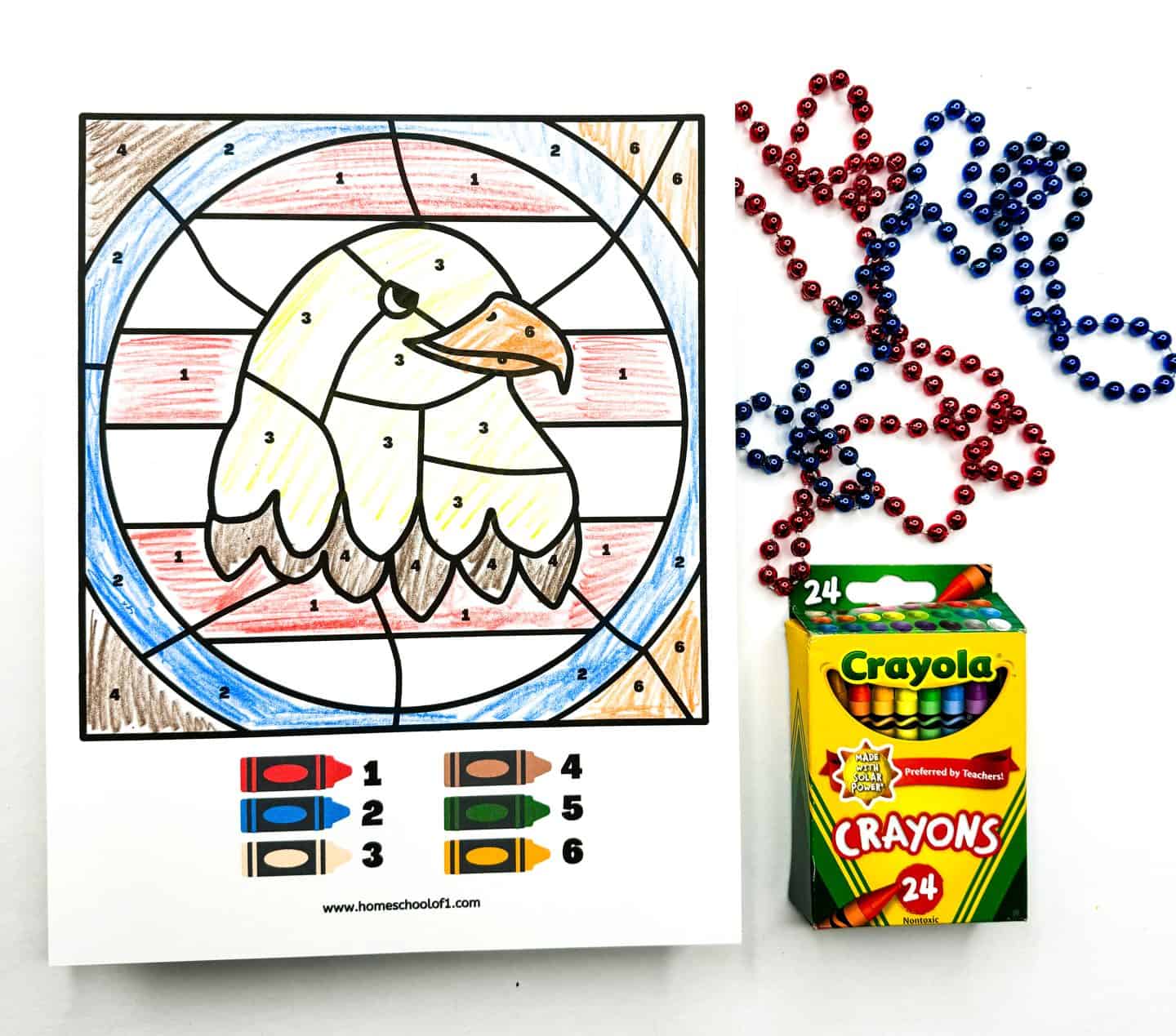 bald eagle color by number completed with 6 different colors and red and blue beads and crayola crayons sit next to it. 