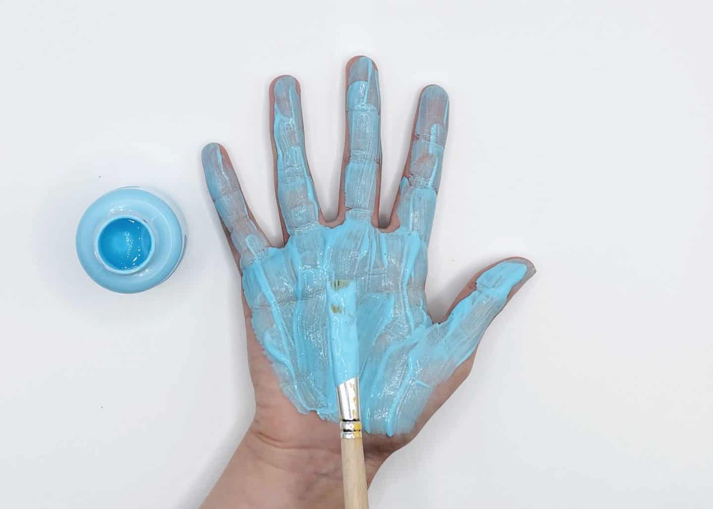 a childs hand being painted blue with handprint paint