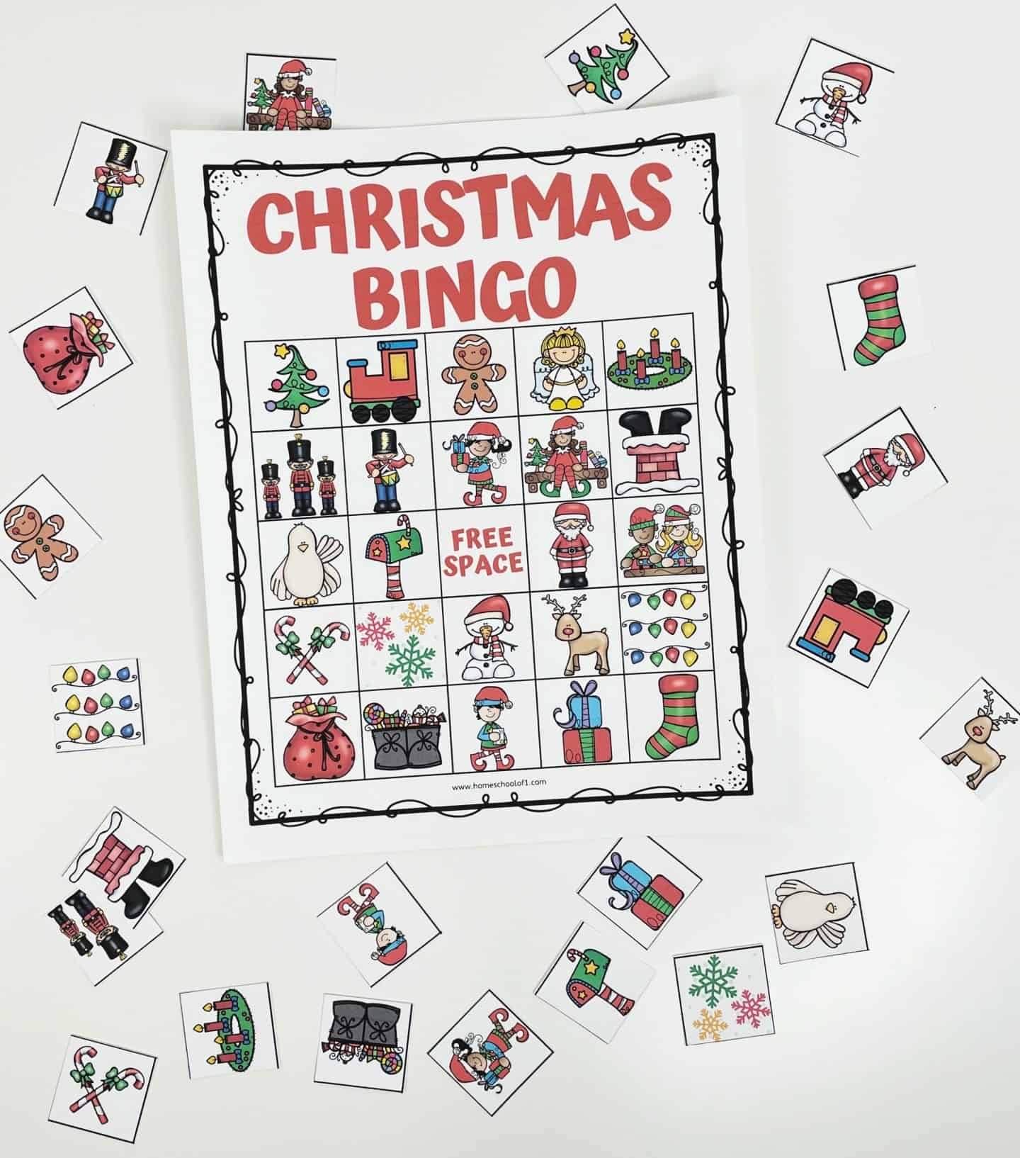 A Christmas Bingo game board is displayed at the center, featuring a 5x5 grid filled with festive illustrations like Santa, gingerbread cookies, stockings, presents, elves, and more. The board includes a “Free Space” in the middle. Surrounding the board are individual calling cards scattered on the surface, each showing a matching holiday image. The bright and cheerful setup is perfect for a Christmas-themed classroom or family activity.