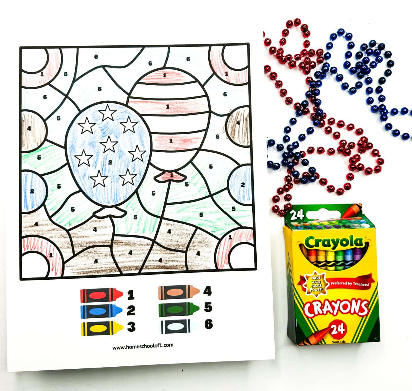 patriotic balloons color by number worksheet completed with 6 different colors and red and blue beads and crayola crayons on the side for decoration. 