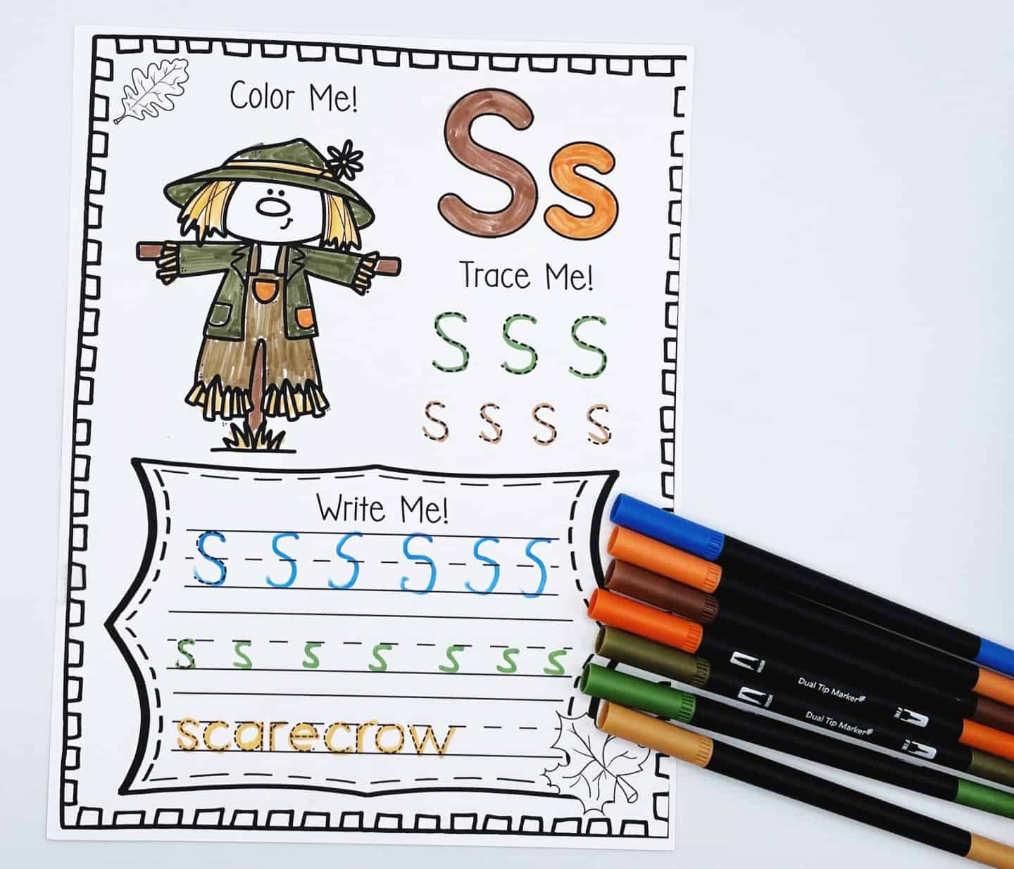 Fall alphabet worksheet for the letter S with a scarecrow coloring activity, uppercase and lowercase S tracing, and handwriting lines for practicing the word “scarecrow.” Autumn-themed colors and markers make this an engaging literacy tool for kids.