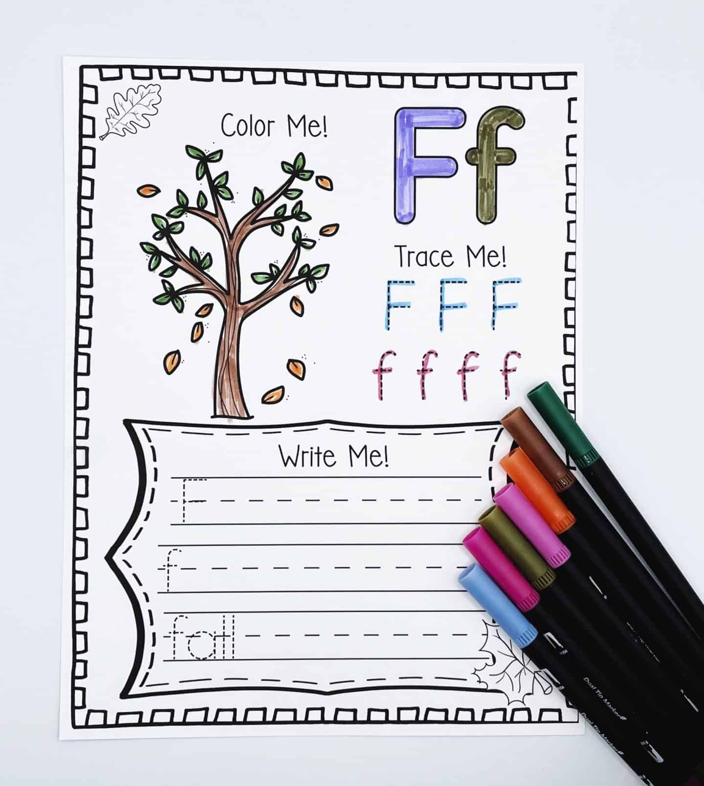 Fall alphabet worksheet for the letter F showing a tree with falling leaves to color, uppercase and lowercase F tracing lines, and writing practice for the word "fall." Several colorful markers are placed beside the sheet, reinforcing the seasonal learning theme.







