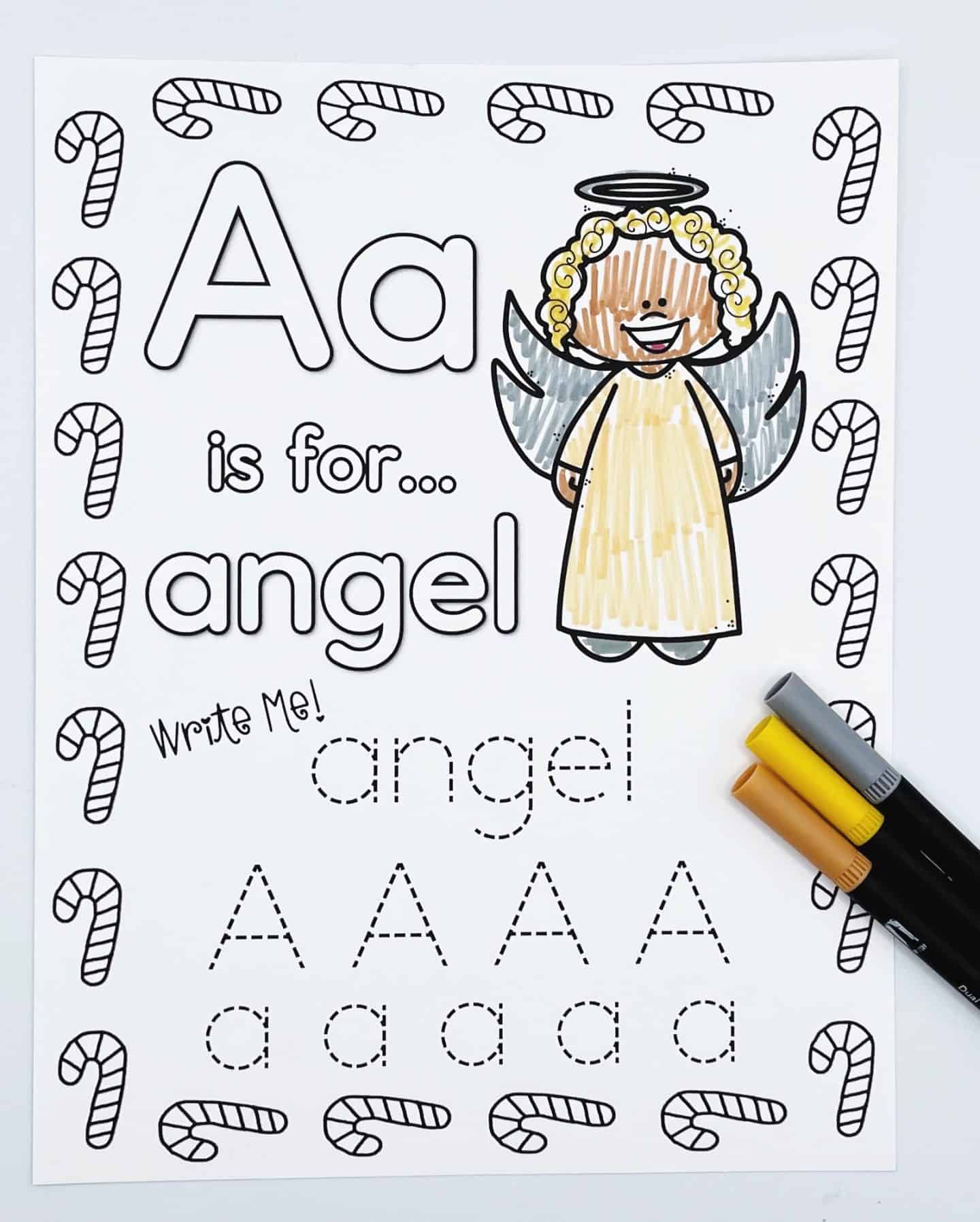 A Christmas-themed alphabet worksheet focused on the letter A, featuring the phrase “A is for… angel.” The page includes a smiling angel with curly yellow hair, a halo, and gray wings. Children can trace the word "angel" and uppercase and lowercase A’s. The worksheet is decorated with candy canes and includes yellow, gray, and brown markers on the side.