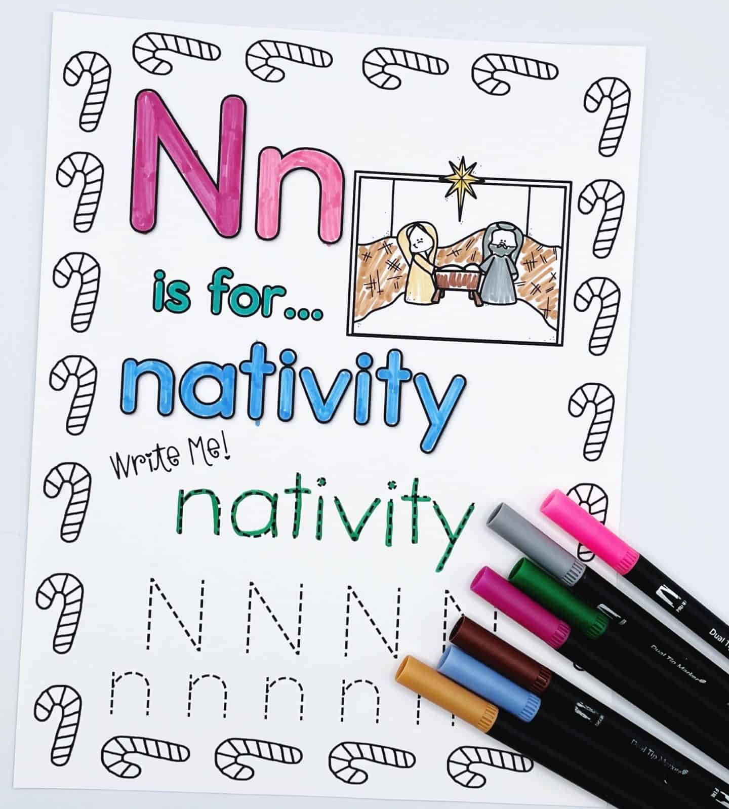 Christmas alphabet worksheet for the letter N, with the phrase “N is for… nativity.” The page includes a colored nativity scene with Mary, Joseph, and baby Jesus under a star, along with traceable writing practice for the word "nativity" and both uppercase and lowercase N’s. Candy canes decorate the border, and several colorful markers are placed in the corner.