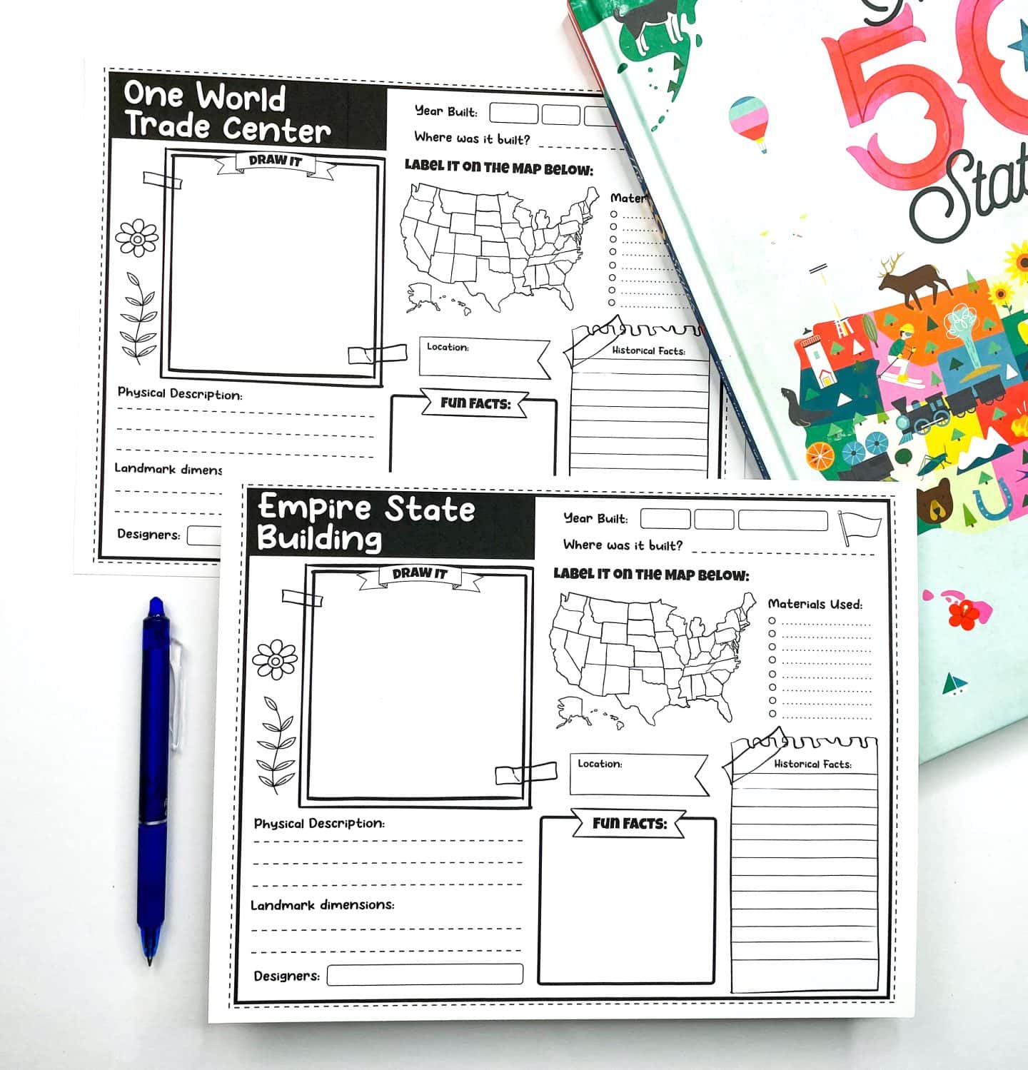 Two printable U.S. landmark worksheets for kids featuring the One World Trade Center and the Empire State Building. Each worksheet includes a space to draw the landmark, label its location on a U.S. map, and fill in sections for physical description, materials used, fun facts, historical facts, landmark dimensions, and designers. A blue pen and a colorful book titled “The 50 States” are included in the background.

