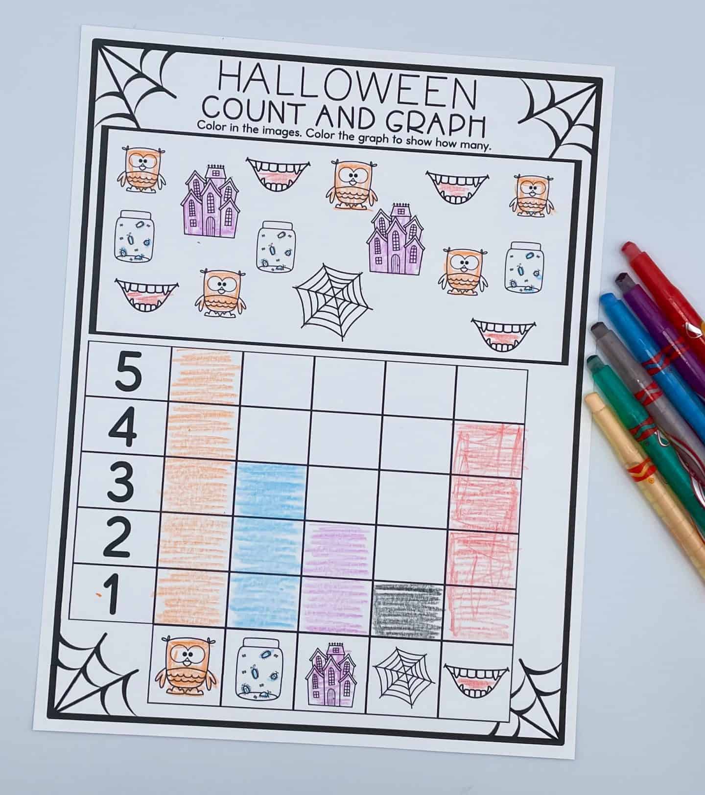 A Halloween “Count and Graph” worksheet featuring cute illustrations of owls, haunted houses, jars with eyes, spiderwebs, and vampire mouths. Each image type is represented in a colorful bar graph at the bottom using orange, blue, purple, black, and red shading. A set of colorful pens lies to the right of the page, completing the festive and educational activity.