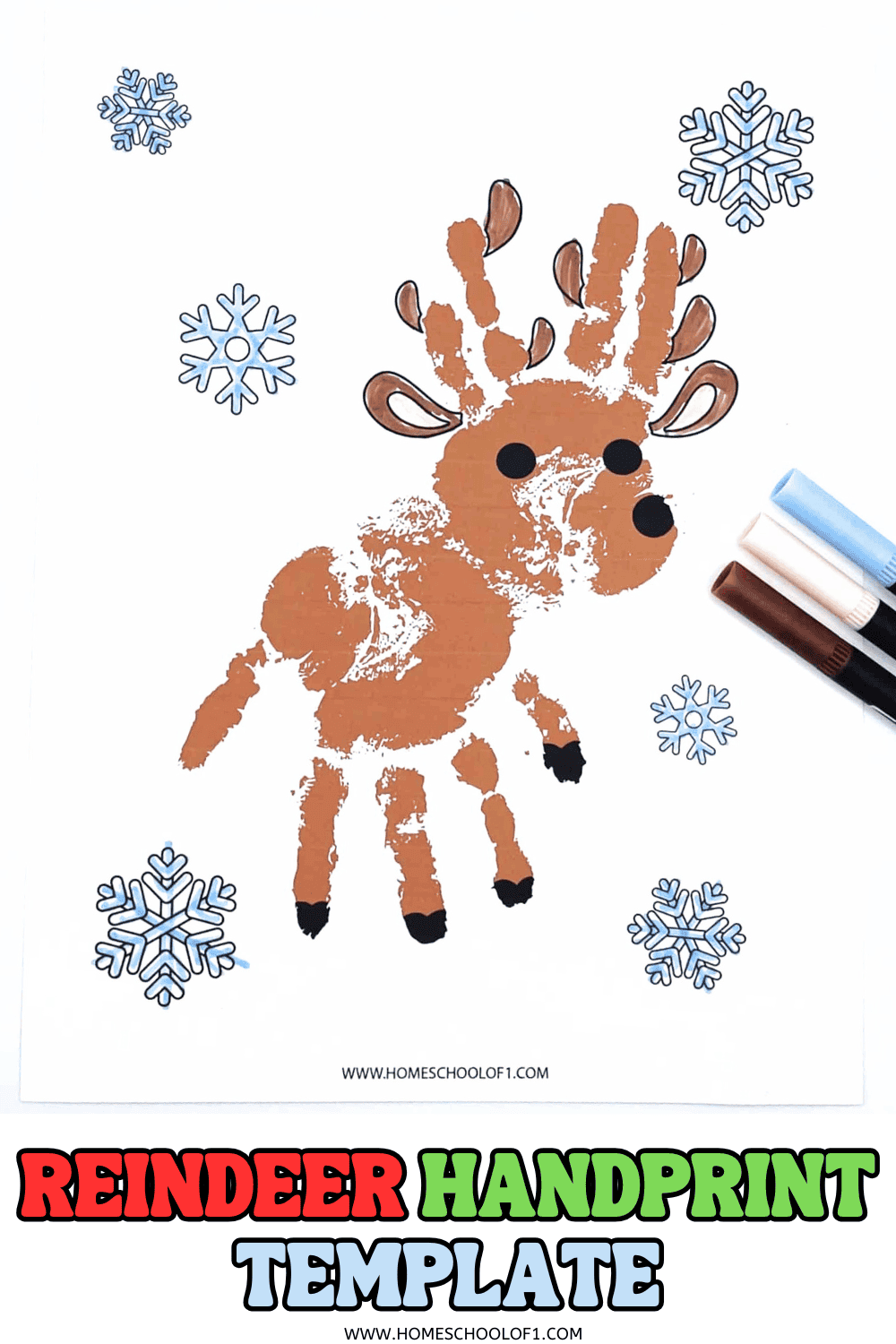 Two painted hands ready to stamp on a reindeer handprint template with snowflake designs, crayons, and a Christmas book.

