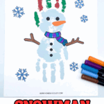 Completed snowman handprint craft with red and green painted fingers, orange carrot nose, scarf, and markers alongside.