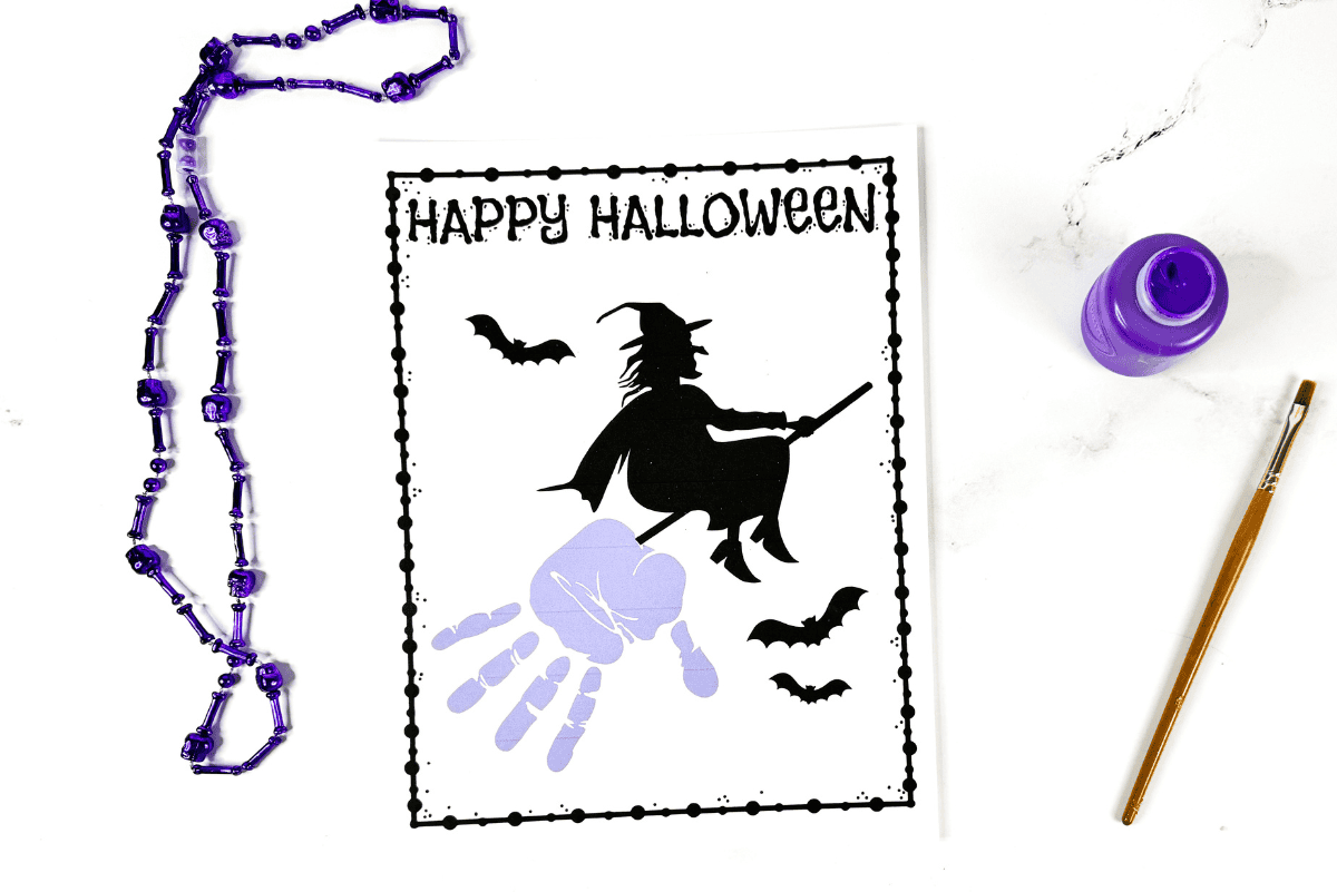 Free printable witch handprint template with flying witch and purple handprint on broom