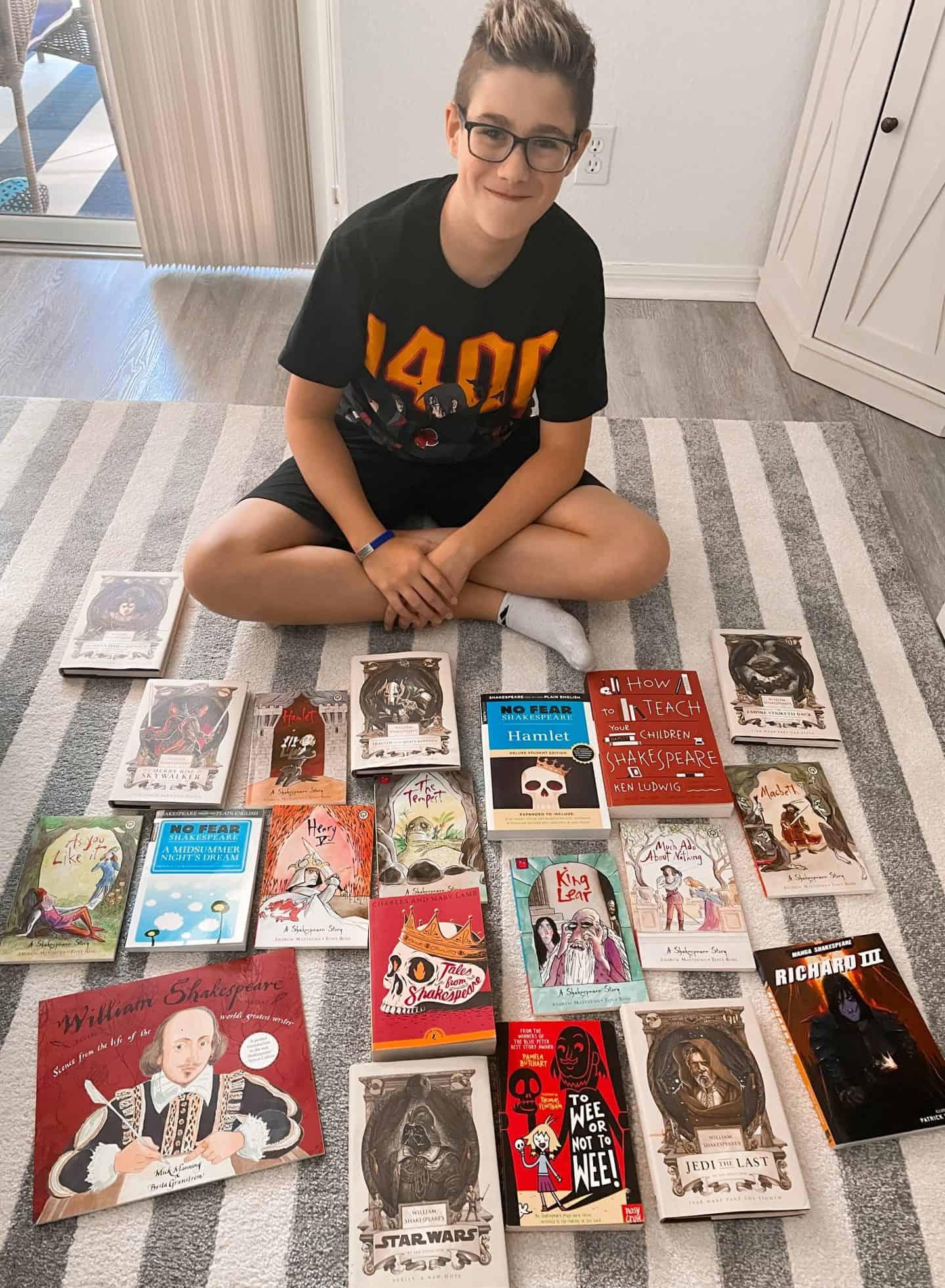 Boy sitting on a rug surrounded by his favorite Shakespeare books such as King Lear graphic novel, William Shakespeare's Star Wars, Richard III graphic novel, No Fear Shakespeare A Midsummer Nights Dream