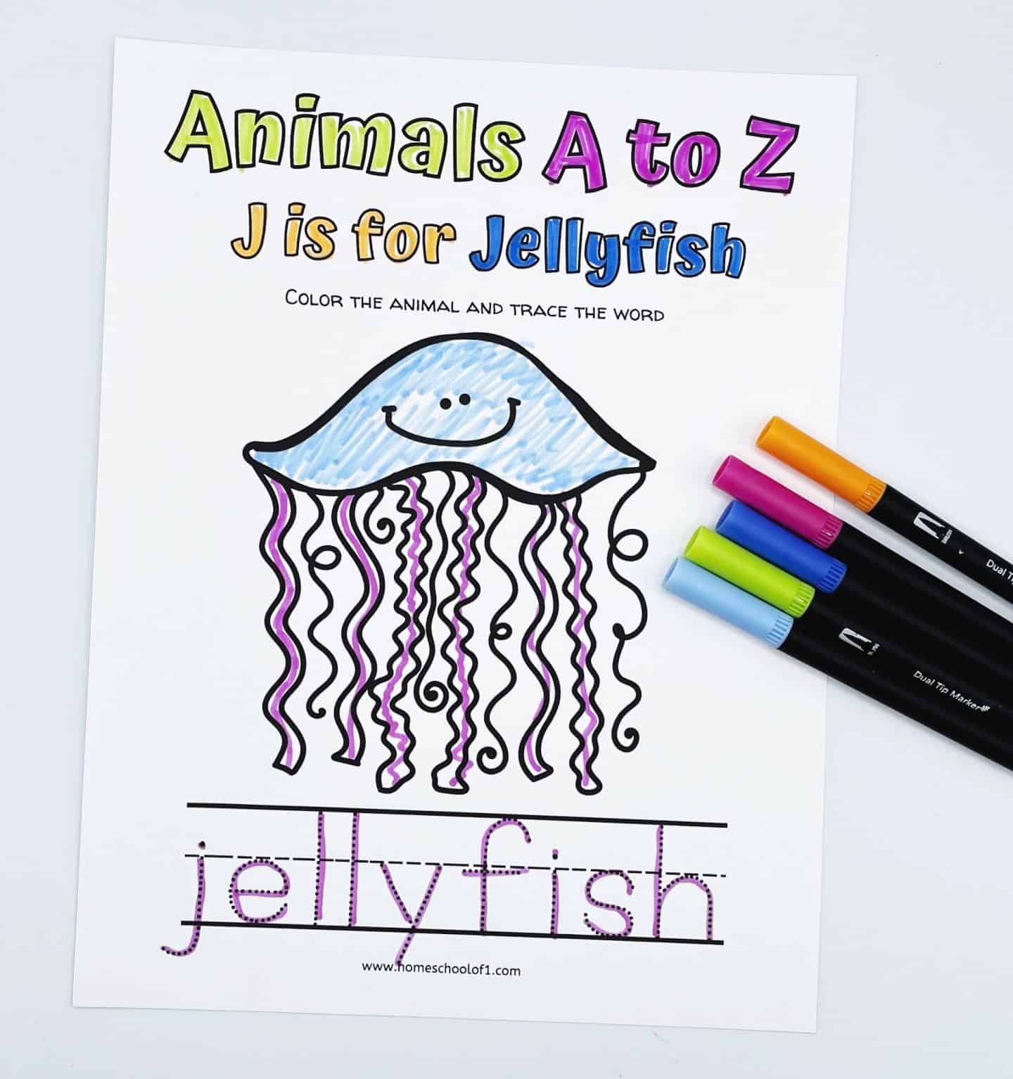 "J is for Jellyfish" coloring worksheet from the Animals A to Z series, featuring a smiling jellyfish with a blue bell and purple tentacles. The worksheet prompts kids to color the animal and trace the word “jellyfish,” which is written in dotted lines. Five colorful markers lie beside the worksheet.