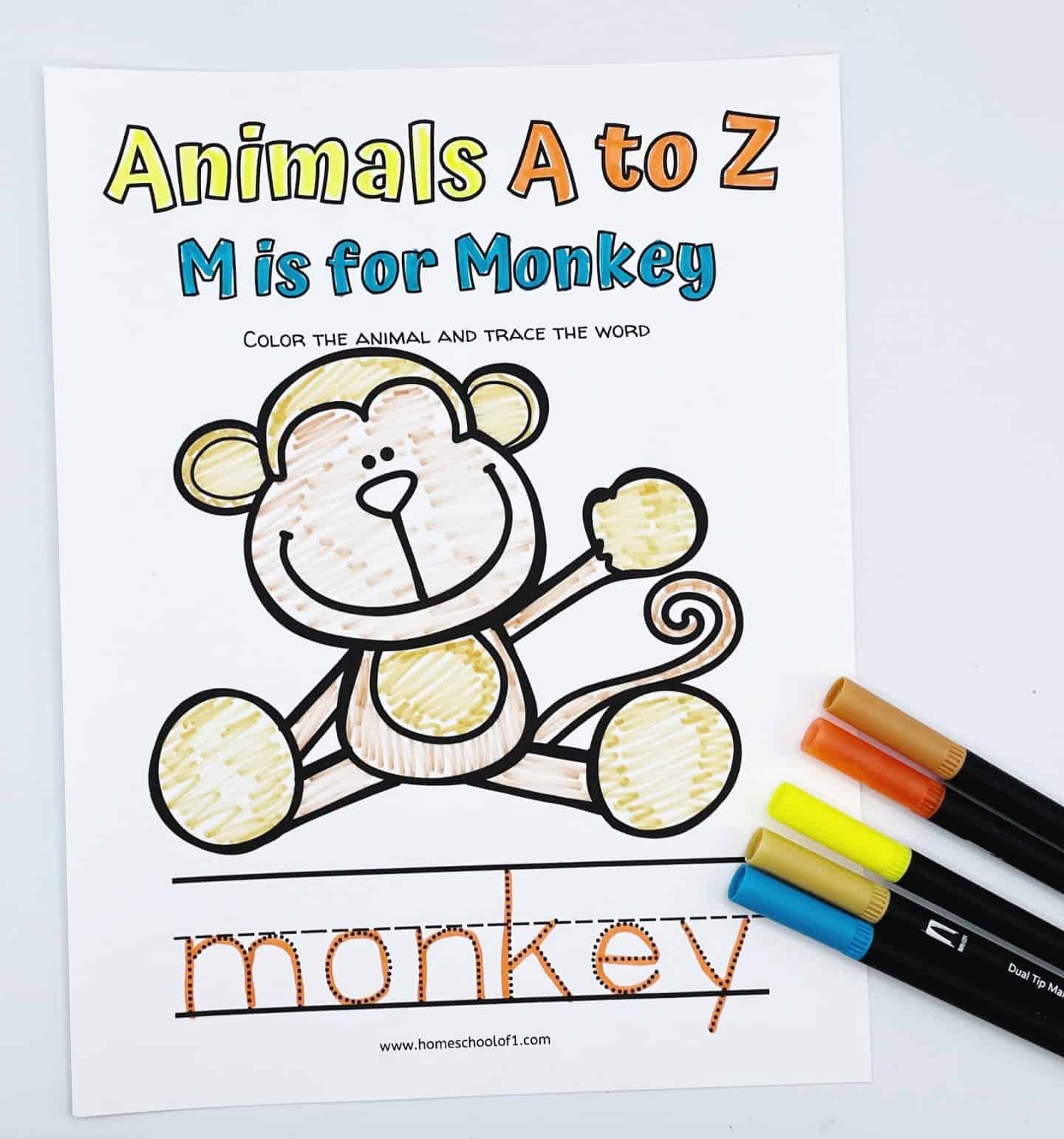 "M is for Monkey" coloring worksheet from the Animals A to Z series, showing a cute cartoon monkey with a tan and brown body. Children are prompted to color the animal and trace the word “monkey,” which appears in dotted lines below. Five markers in earthy tones lie beside the page.