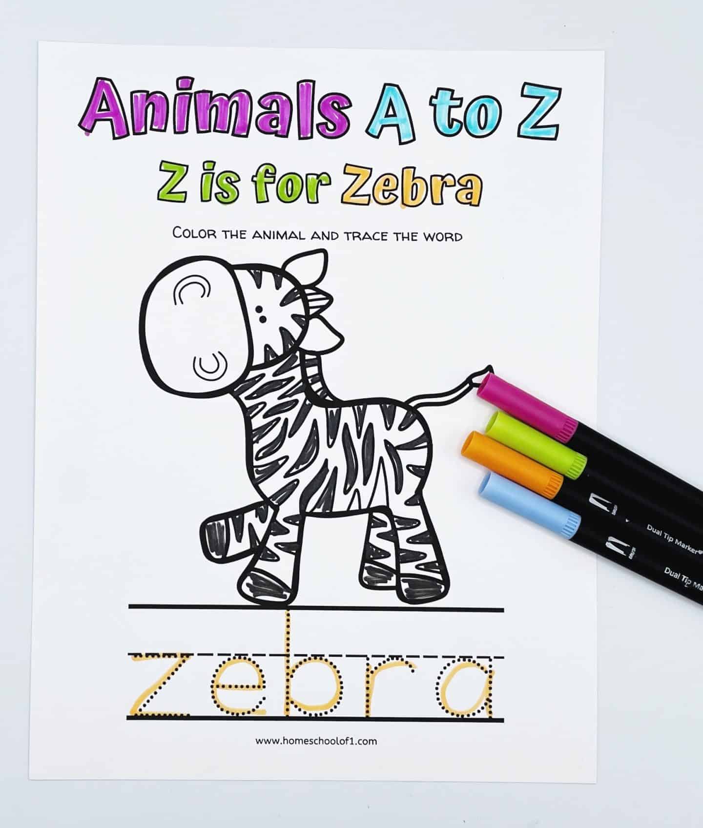 “Z is for Zebra” coloring worksheet from the Animals A to Z series, featuring a smiling cartoon zebra with black stripes partially colored in. The word “zebra” appears below in a dotted tracing font. Four colorful markers—pink, green, orange, and blue—are placed on the right side of the page.