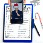 Teen holding phone with Santa selfie over printable Christmas photo scavenger hunt checklist, clipboard, candy cane, and snowflake.
