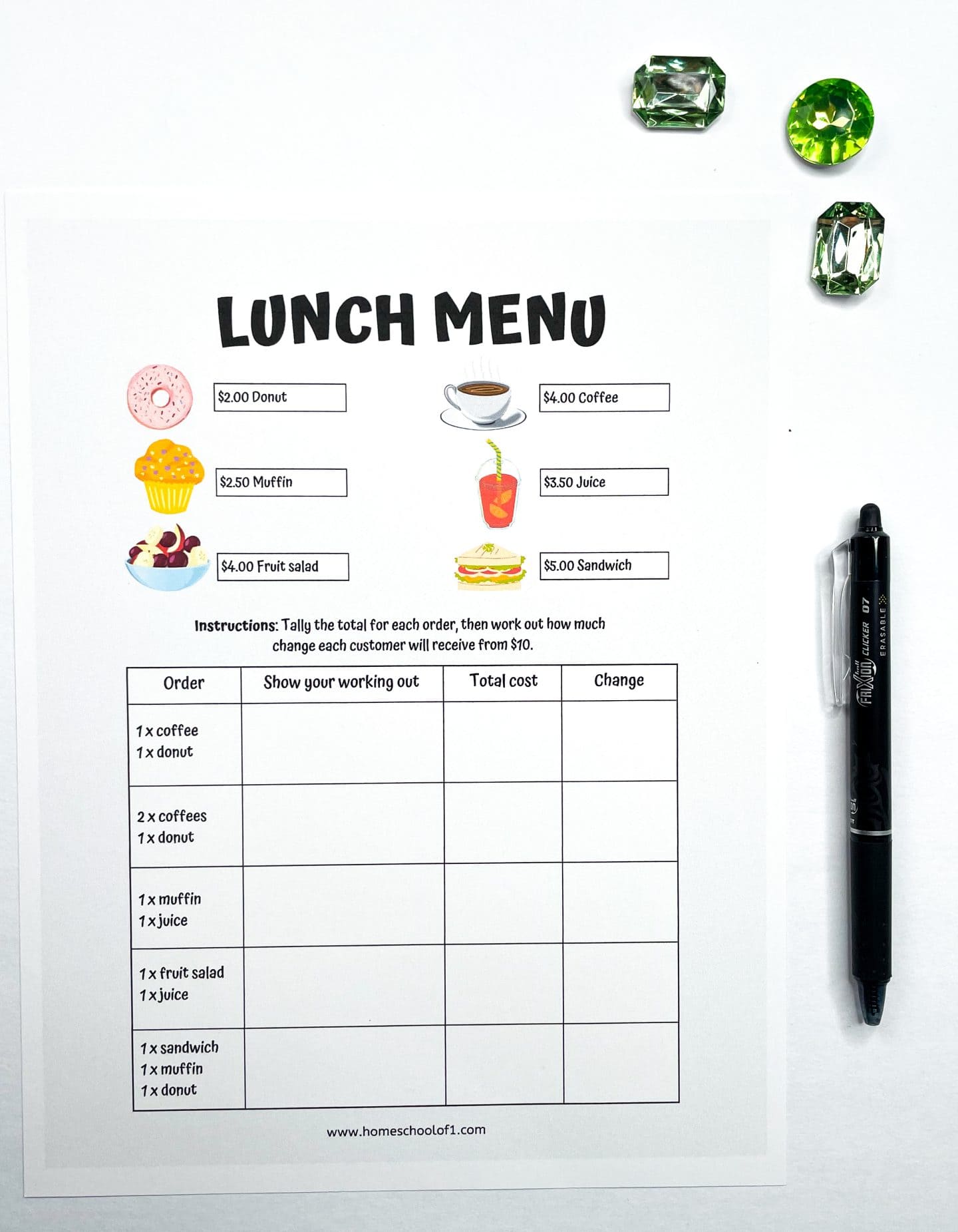 A printable worksheet titled "Lunch Menu" displays six illustrated food and drink items with prices: donut ($2.00), muffin ($2.50), fruit salad ($4.00), coffee ($4.00), juice ($3.50), and sandwich ($5.00). Below is a table with five pre-filled order combinations where students calculate total costs and determine the change from $10. A pen and green plastic gems sit beside the worksheet.