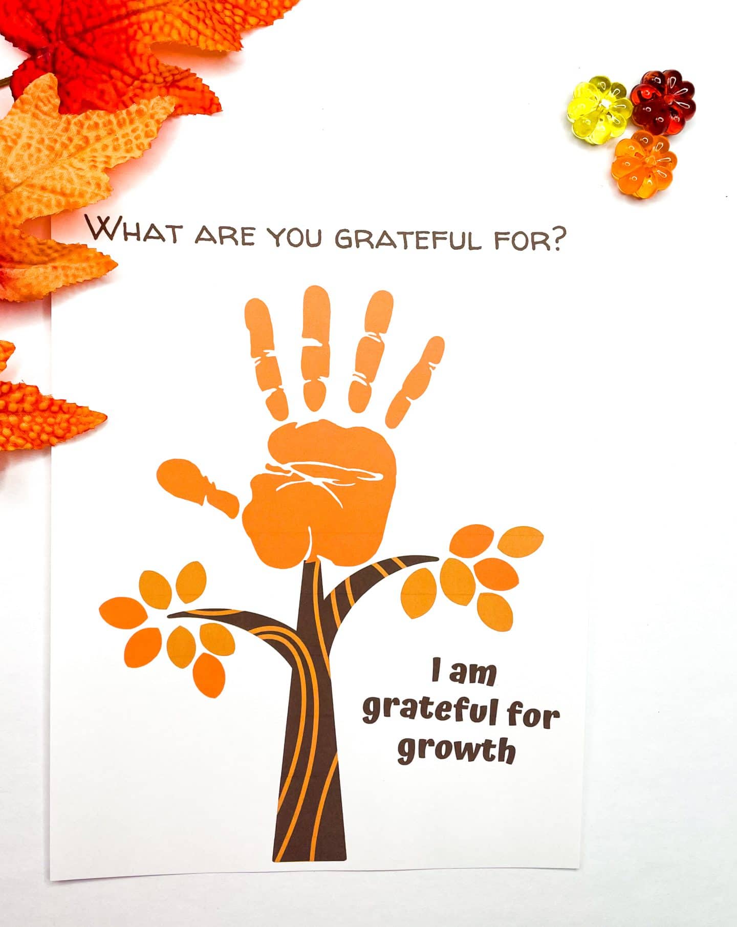 what are you grateful for? then an orange handprint as the fall leaves of the tree and then the words i am grateful for growth. surrounded by red and orange foliage.