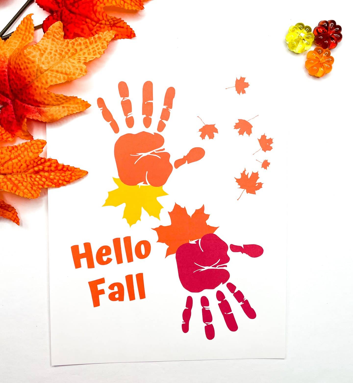 completed thanksgiving handprint hello fall art with orange foliage and orange red and yellow pumpkins.