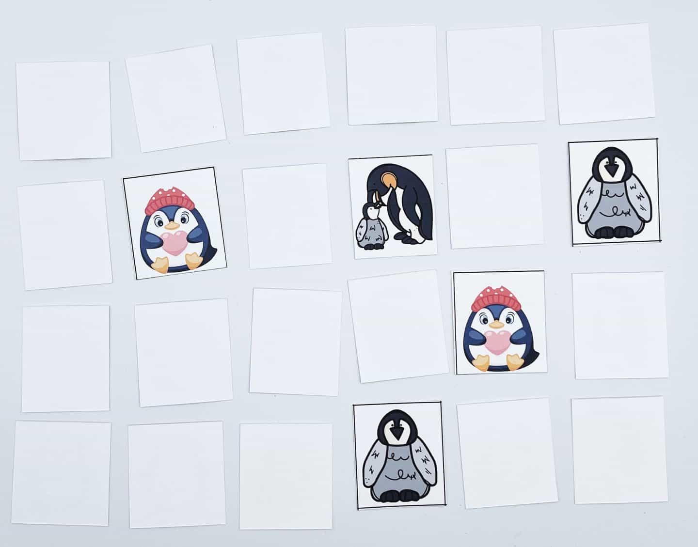 A memory card game with rows of face-down cards and three face-up cards showing penguins. One card has a penguin with a red hat, another has a penguin family, and the third has a penguin with a unique beak design.
