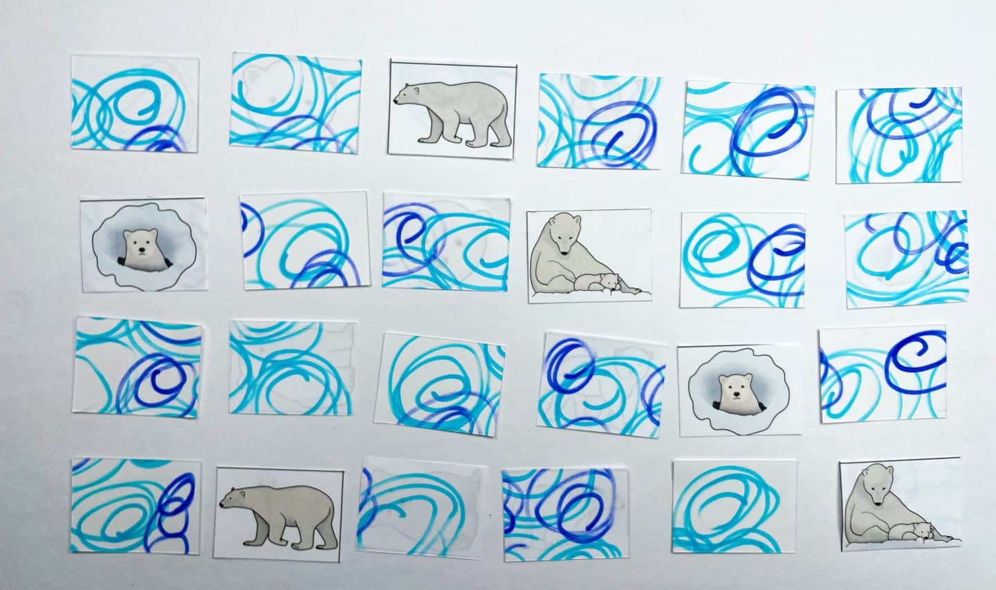 a completed "Polar Bear Memory Game." The game cards have been printed and cut out, with polar bear illustrations alongside abstract blue and purple swirl designs. The objective is to match identical images of polar bears in various stages of life, such as a bear cub in a den, a mother with a cub, and an adult polar bear.