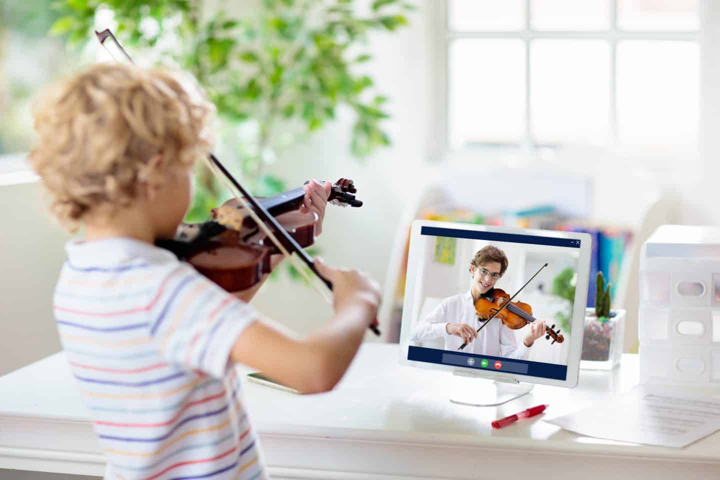 Child playing violin. Remote learning.