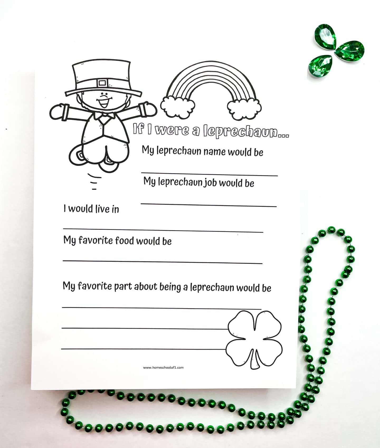 Black and white printable St. Patrick’s Day worksheet titled “If I were a leprechaun…” featuring prompts for kids to fill in their leprechaun name, job, home, favorite food, and favorite part about being a leprechaun. The sheet is decorated with outlined illustrations of a leprechaun, a rainbow, and a shamrock. Green bead garland and gem decorations accent the page for a festive touch.