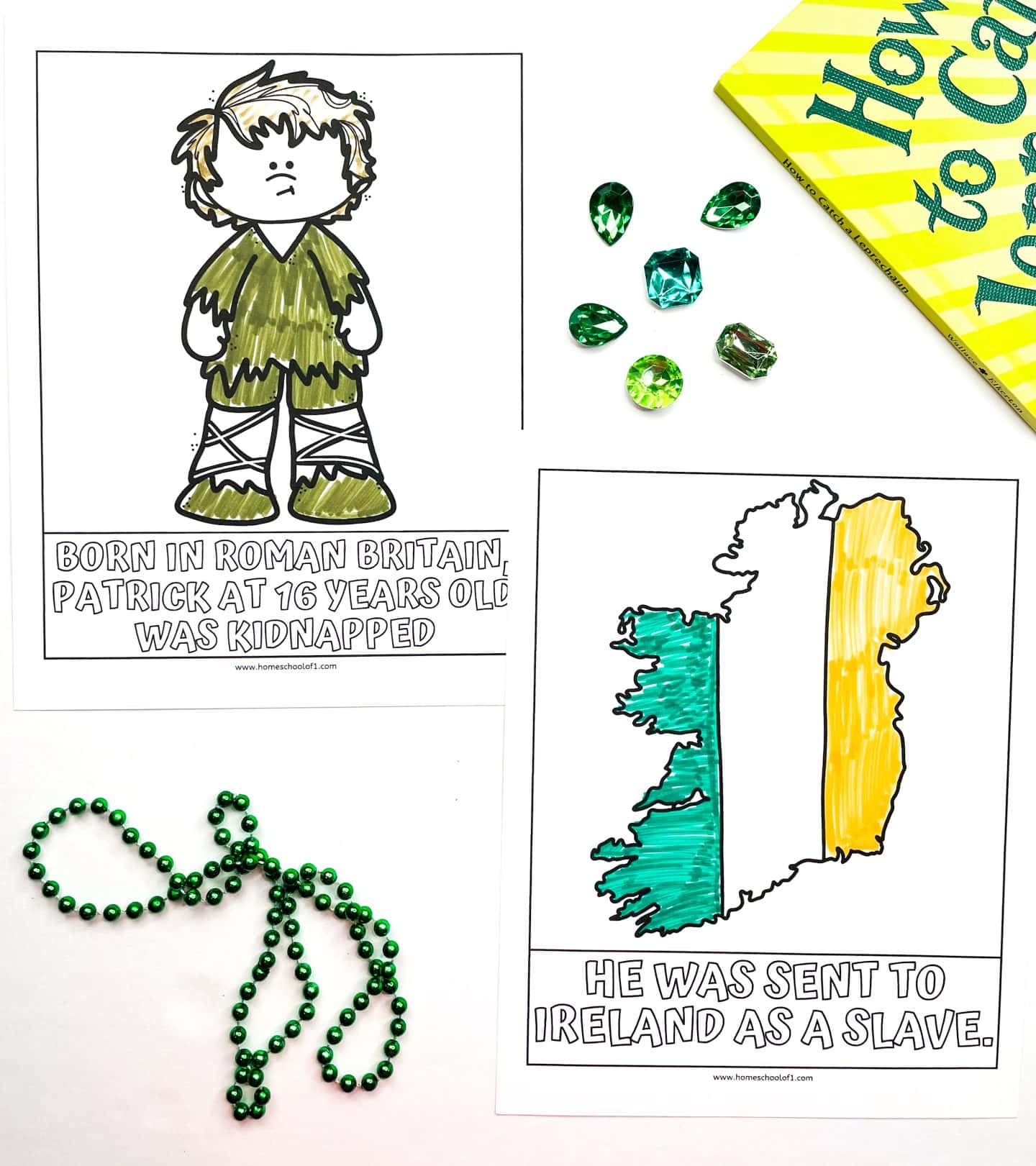 Two St. Patrick’s Day history worksheets for kids are shown, one featuring a cartoon of young Saint Patrick in tattered clothes with the caption, “Born in Roman Britain, Patrick at 16 years old was kidnapped,” and the other showing a colored-in map of Ireland with the Irish flag colors and the text, “He was sent to Ireland as a slave.” The scene includes green bead necklaces, faux emerald gems, and part of a yellow and green book titled “How to Catch a Leprechaun.”

