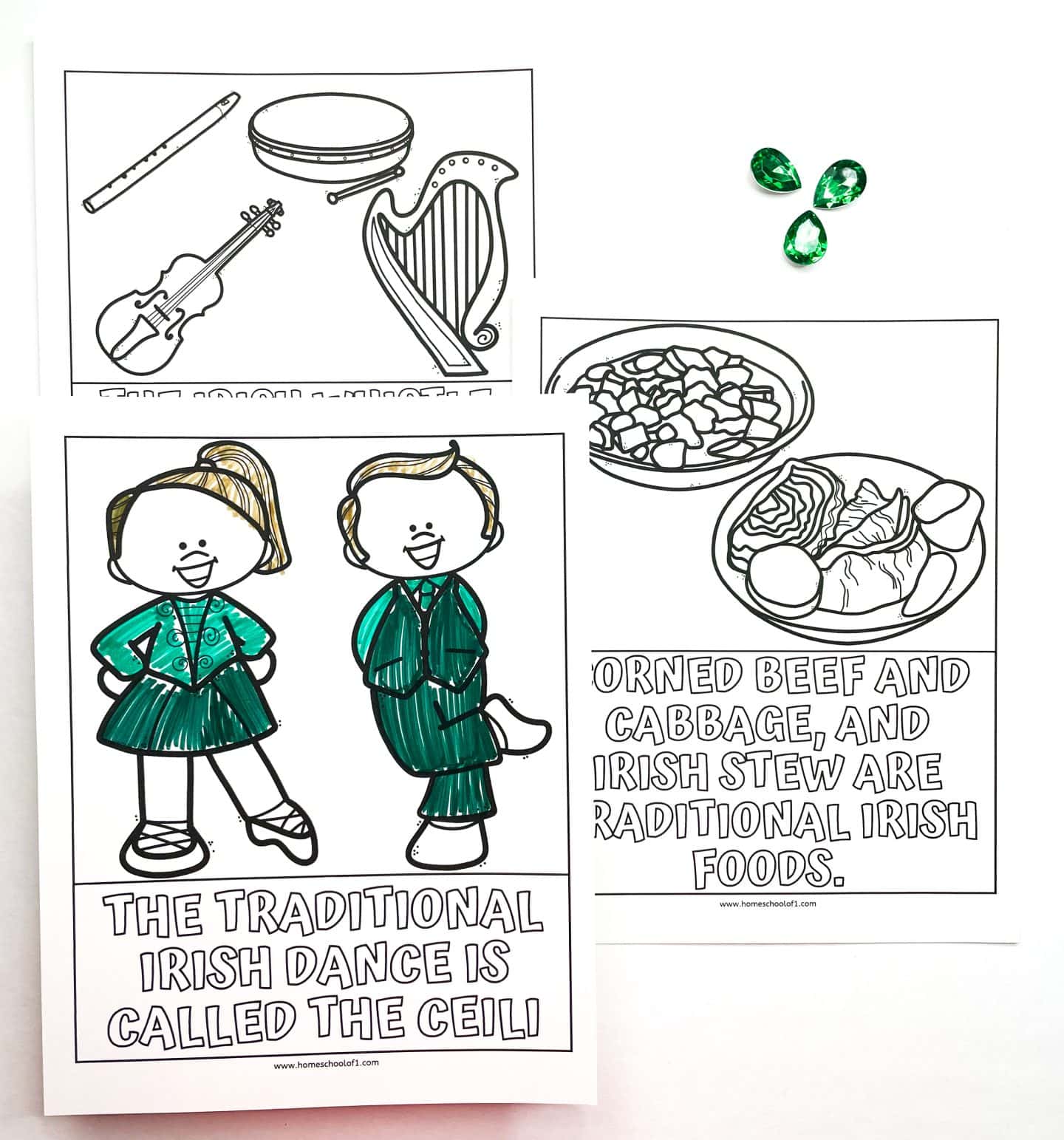 A set of St. Patrick’s Day coloring worksheets for kids, highlighting Irish culture. One worksheet shows two children in traditional Irish dance attire with the caption, “The traditional Irish dance is called the Ceili.” Another depicts corned beef, cabbage, and Irish stew with the caption, “Corned beef and cabbage, and Irish stew are traditional Irish foods.” A third worksheet includes illustrations of Irish instruments like the fiddle, harp, tin whistle, and bodhrán. Three green gem decorations are placed nearby.