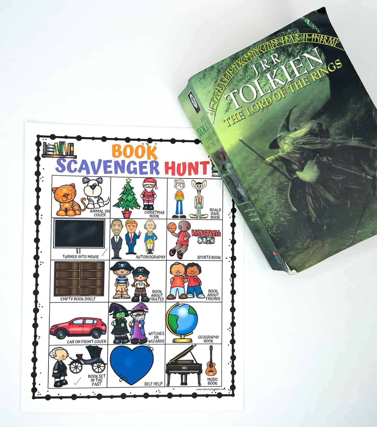 A Book Scavenger Hunt printable is shown on a white surface next to a copy of The Lord of the Rings by J.R.R. Tolkien. The scavenger hunt includes illustrated prompts such as “Witches or Wizards,” “Book Set in the Past,” and “Turned Into Movie,” all of which apply to the Tolkien novel. The activity sheet is colorful and engaging, designed to encourage kids to explore different book themes during library or reading time.